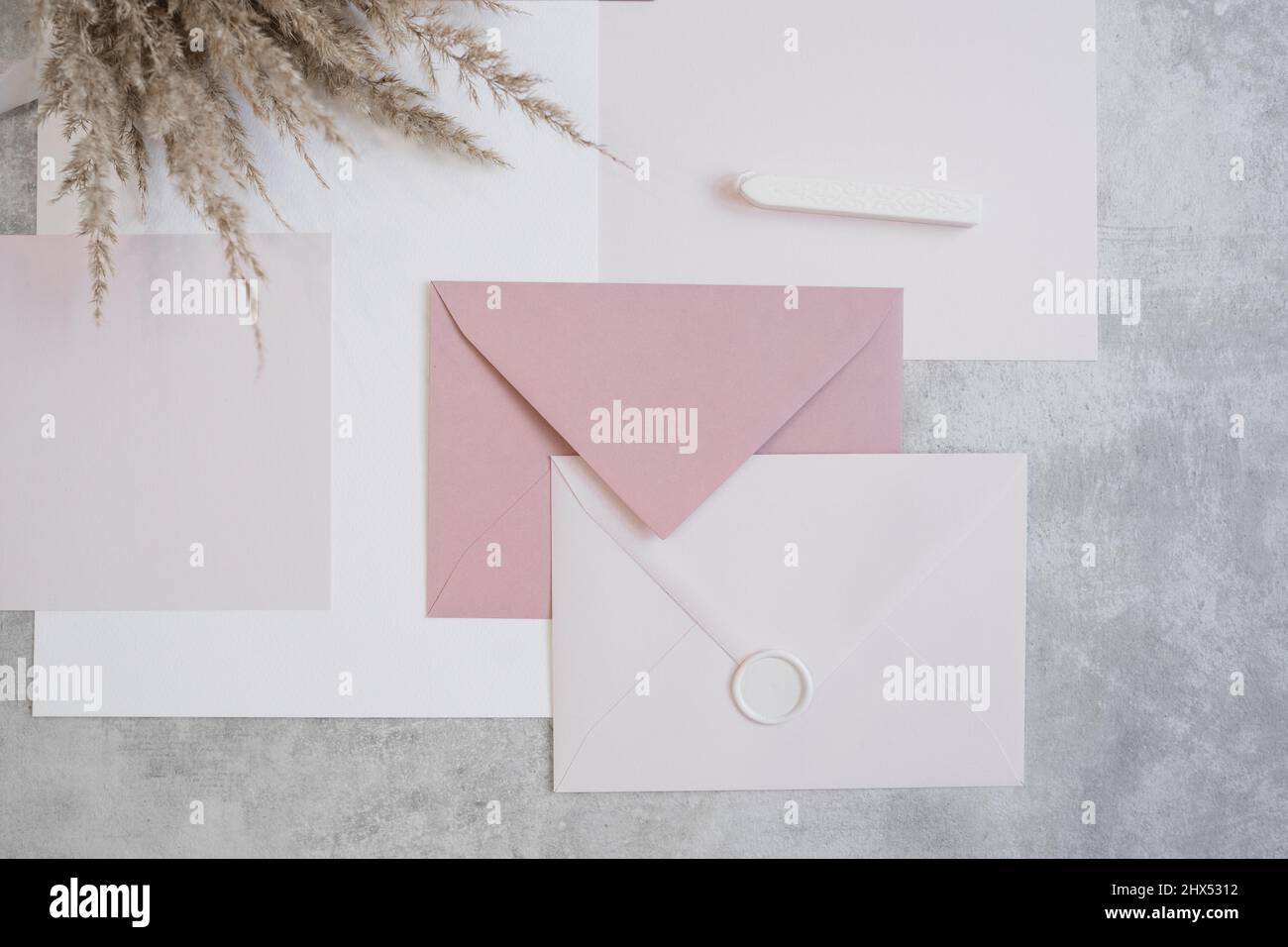 Vista dall'alto della composizione di fogli di carta di diverse dimensioni, buste bianche e rosa sigillate con cera, cera sigillante. Foto Stock