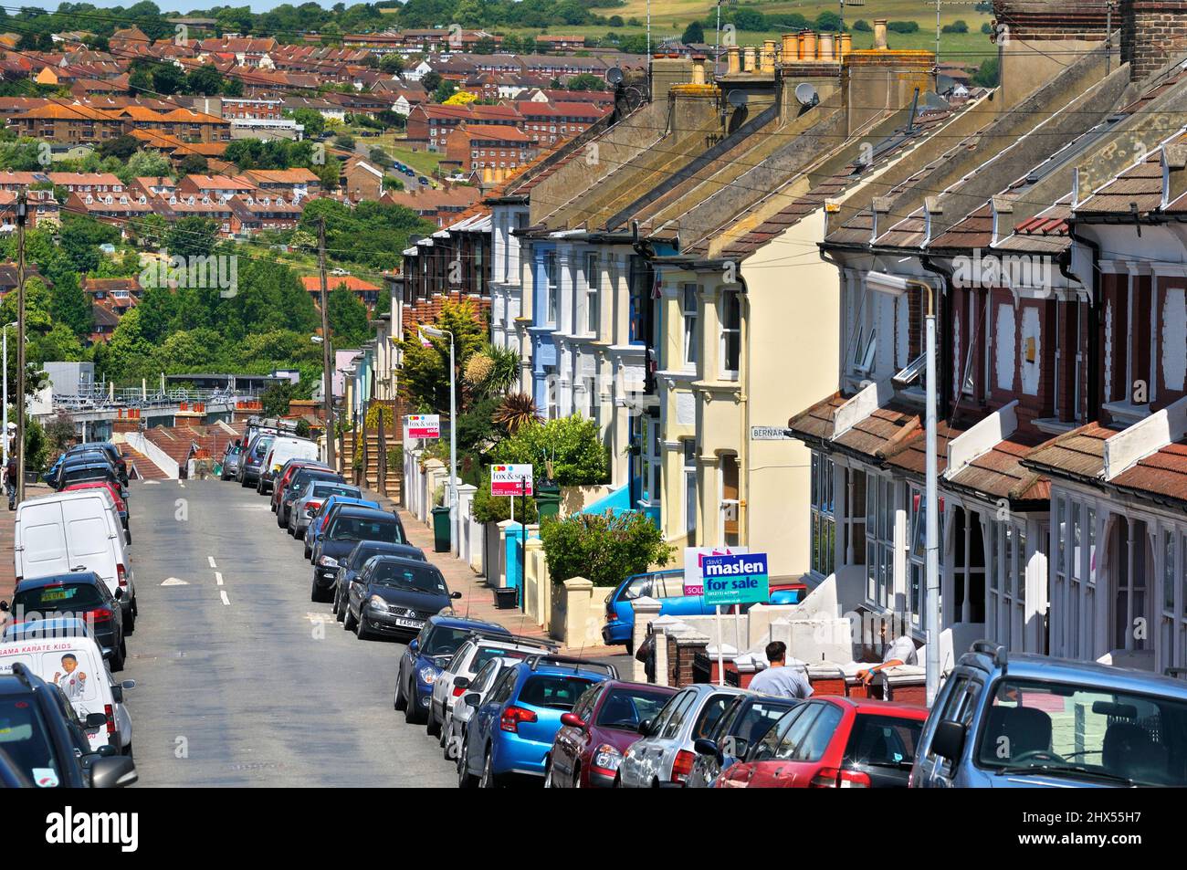 Case a schiera e cartelli di agenti immobiliari (in vendita e venduti) su una tipica strada residenziale suburbana, Kemptown, Brighton, East Sussex, Inghilterra, REGNO UNITO Foto Stock