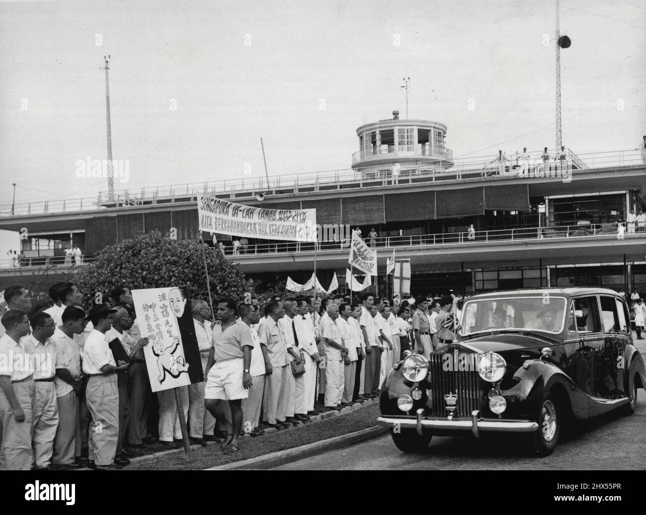 I manifestanti di Singapore incontrano Lennox-Boyd Un gruppo di silenti cinesi hanno striscioni che dicono "vogliamo i diritti di cittadinanza, vogliamo l'indipendenza e i diritti di franchising” come segretario coloniale britannico allant. Lennox-Boyd lascia l'aeroporto di Singapore in auto al suo arrivo dal Borneo, il 16 agosto. Il sig. Lennox-Boyd è arrivato per incontrare il governatore di Singapore Sir Robert Black e il Premier di Singapore David Marshall, che erano nel bel mezzo di una disputa. La disputa è stata risolta da Sir Robert's che acconsente a essere guidata dai desideri del Premier di Singapore. Agosto 26, 1955. (Foto per stampa associata) Foto Stock