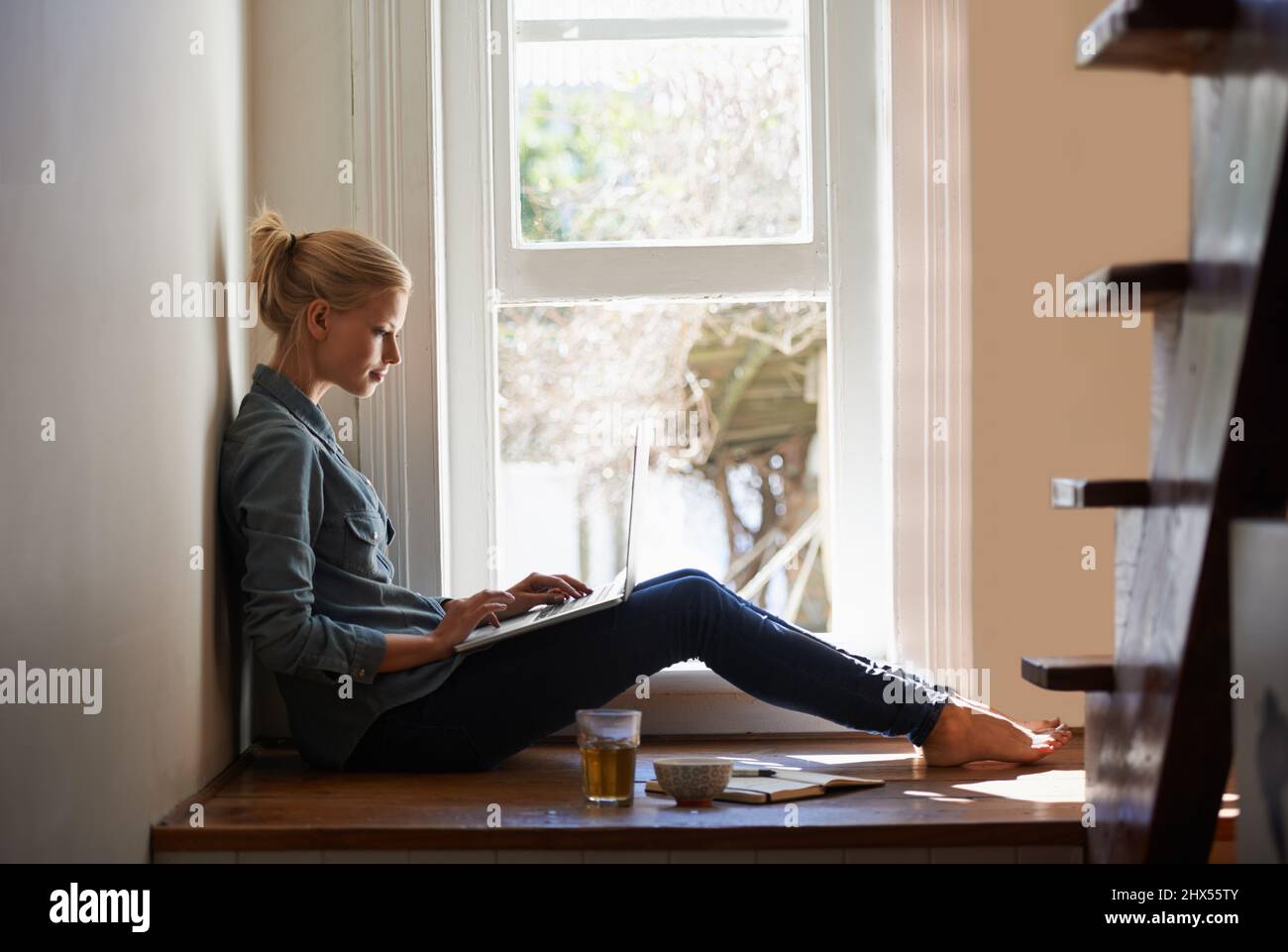 Utilizzo del mio laptop per lavorare da casa. Una giovane donna che usa il suo laptop a casa. Foto Stock
