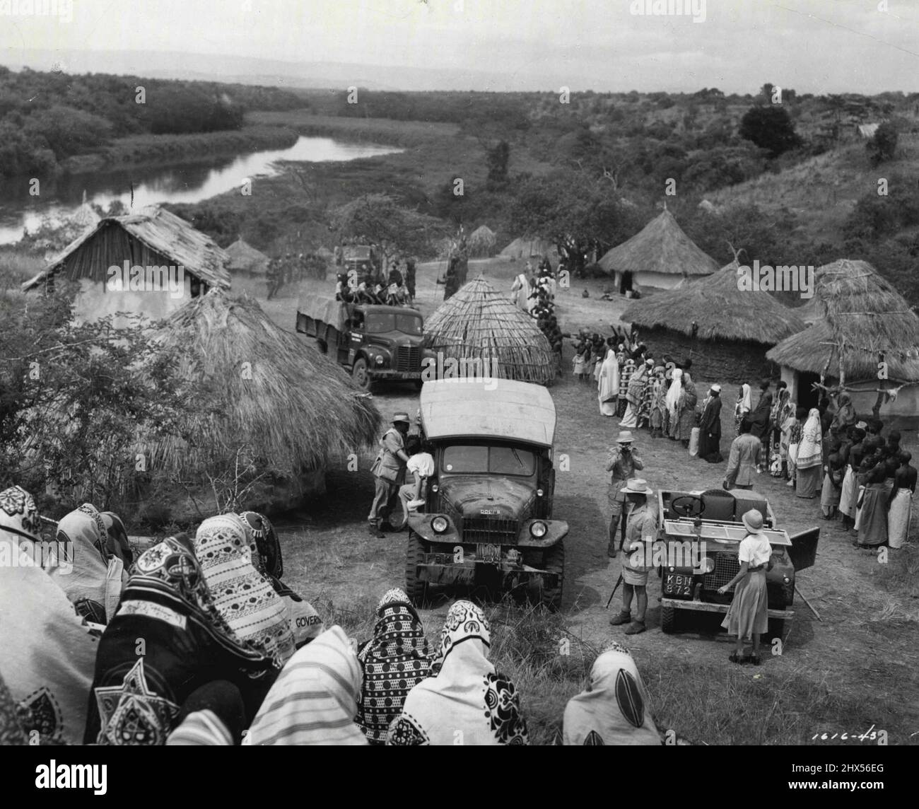 Village Arrival......in questa scena dal 'Mogambo' di M-G-M, girato in Africa, Clark Gable e i membri della sua festa safari sono appena arrivati in un piccolo villaggio nativo. Gable, pistola trasportante, stenos in primo piano, come Donald Sinden, membro del suo partito, fa la sua fotografia. AVA Gardner sta per uscire dal veicolo a sinistra.John Ford ha diretto il film Technicolor con Sam Zimbalist produzione. Ottobre 31, 1953. Foto Stock