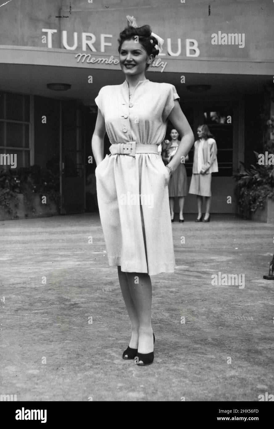 Tuta pista -- adeguatamente, questo piccolo numero pulito (il vestito, naturalmente) è chiamato 'tempo di vincita.' Progettato da Lynn Lester, designer californiano, è modellato dall'esclusivo Turf Club di Hollywood Park. L'abito è di seta grezza, ha maniche di berretto, tasche a slash e cintura rivestita in pelle. Norma Crieger è il modello. Indossa un sorriso vincente per abbinare il vestito. Gennaio 13, 1946. (Foto di Arthur Sasse, International News Photo). Foto Stock