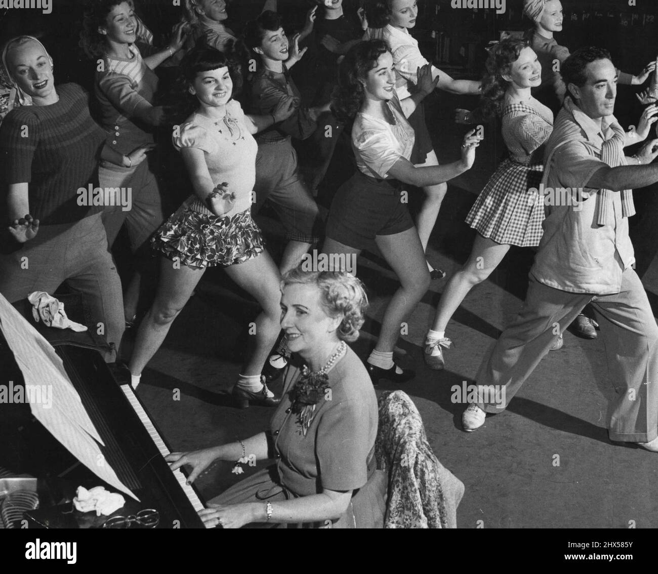 Sotto: Le ragazze del balletto scendono alle prove per la riapertura del Tivioii il venerdì notte. Il maestro del balletto, Ronald Hay, guida questa bevia di bellezza in una nuova routine con l'accompagnamento di Nancy Kerr al pianoforte. Il teatro è stato chiuso durante le ultime restrizioni elettriche. Settembre 08, 1949. Foto Stock