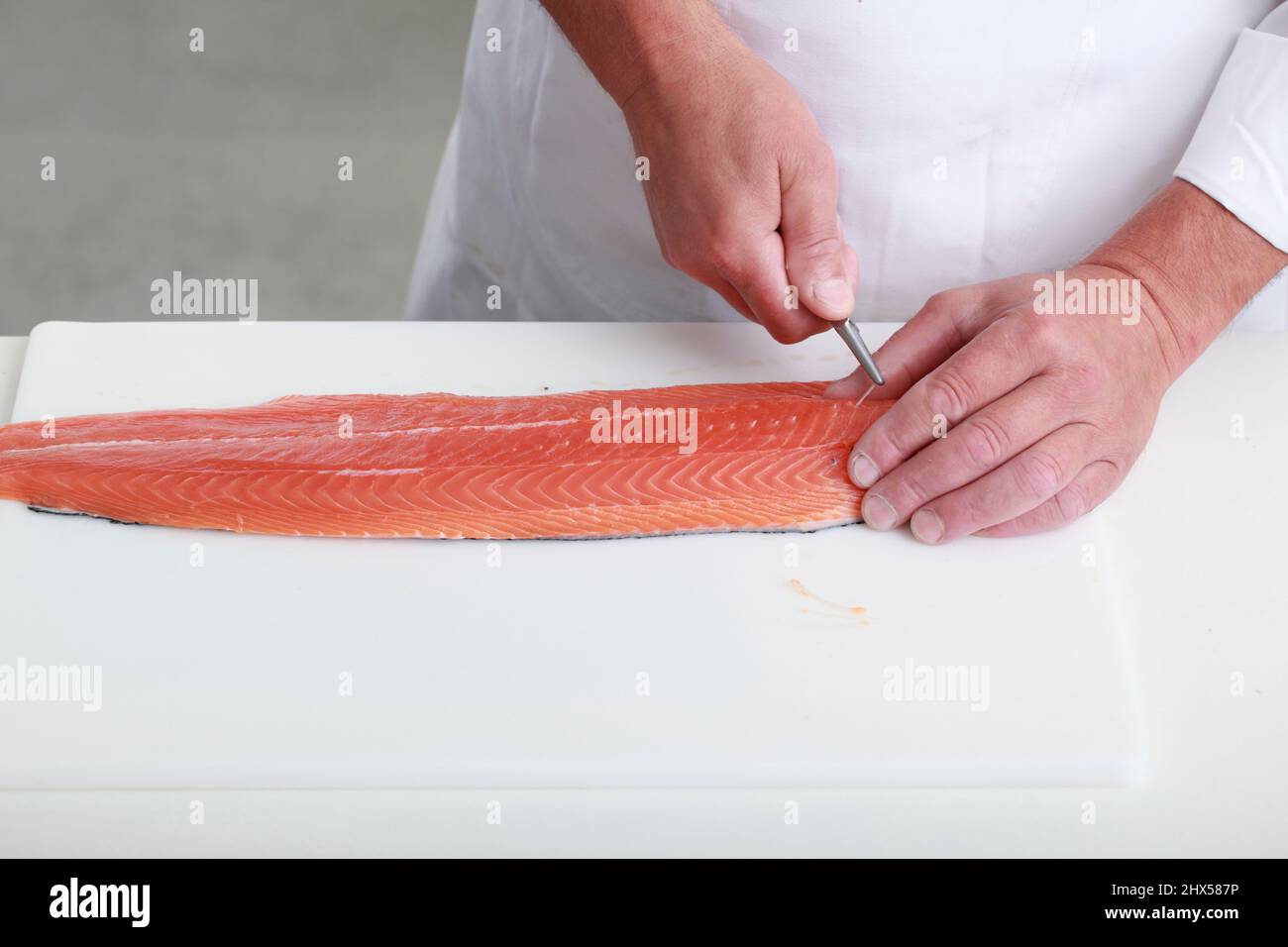 Pinboning filetto di salmone, afferrando l'osso con i pinboners e tirando verso la testa Foto Stock