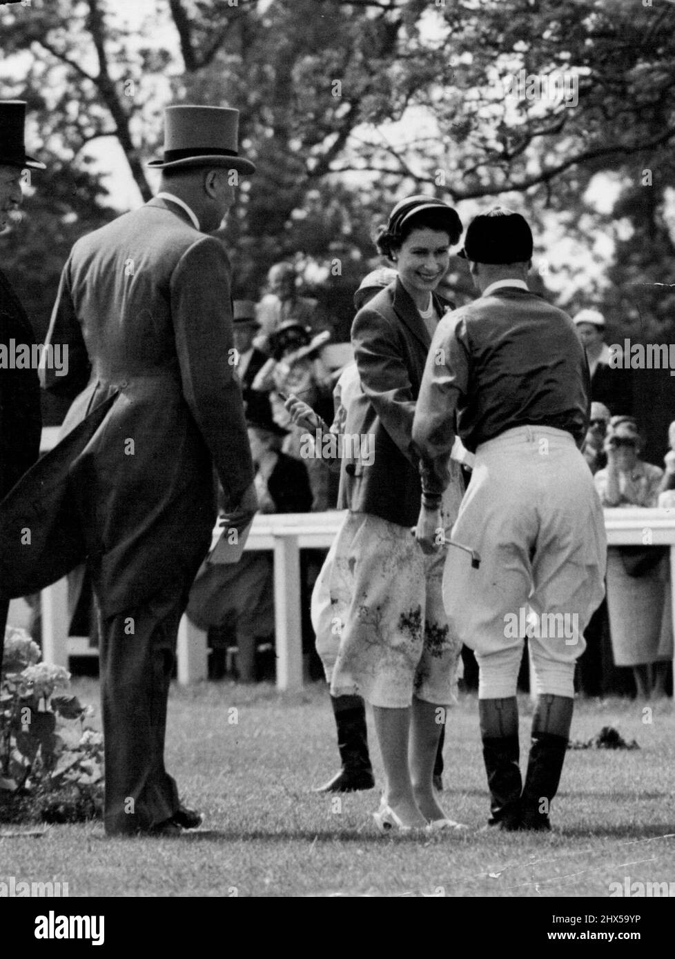 Queen's Handshake per Royal Jockey -- la Regina scuote le mani sorridentemente con il suo jockey, W.H. Carr, nel paddock di Epsom, Surrey, al giorno (Venerdì). Carr stava per cavalcare l'Angelo Sfilly della regina Bright in the Oaks Stakes, il classico delle fillie. È stata spiazzata in gara, che è stata vinta dalla voce francese Sun Cap. Giugno 4, 1954. (Foto di Reuterphoto). Foto Stock