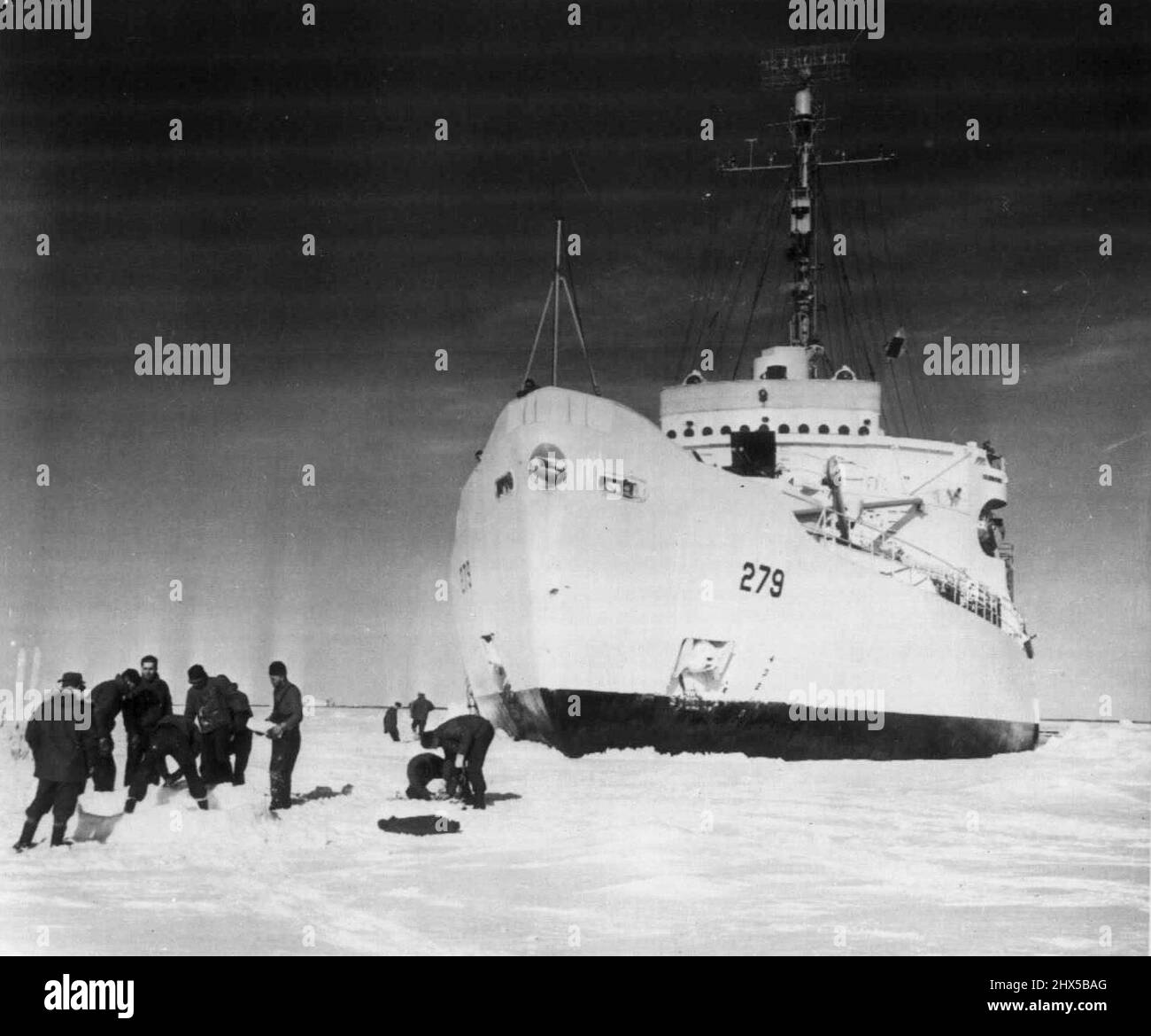 Molo naturale per Icebreaker -- l'icebreaker della Guardia Costiera Eastwind si trova in un molo naturale di ghiaccio in Baffin Bay, mentre i membri dell'equipaggio tentano di soddisfare un desiderio di costruire un igloo Eskimo da blocchi di ghiaccio. L'Eastwind ha aspettato nel ghiaccio, mentre le squadre di cani hanno portato i membri di una missione idrografica nell'isola di Baffin, collegata al ghiaccio, nei territori del nord-ovest del Canada, la scorsa estate. L'Eastwind è stato bloccato da ghiaccio troppo pesante per poter attraversare 25 miglia dalla costa di Baffin Island. Dicembre 29, 1952. (Foto della Guardia Costiera degli Stati Uniti foto). Foto Stock