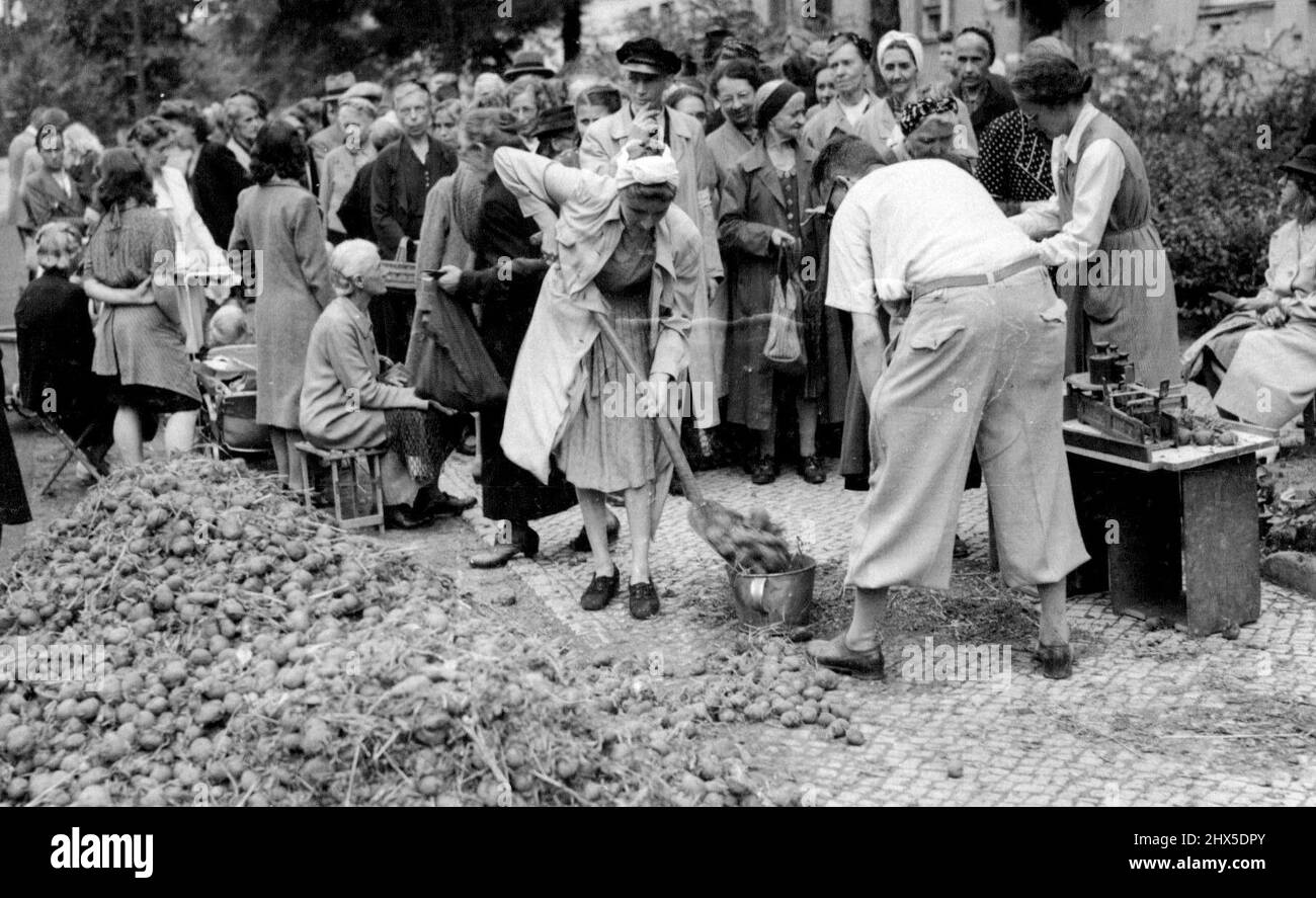 Nessuna vacanza per i tedeschi - civili tedeschi Queuing per la loro razione di patate a Berlino. Una donna è vista che le spala in cestelli, secchi e altri recipienti per pesare. Mentre le stazioni balneari inglesi stanno approvvigionando per le folle record di festa della Banca di agosto in molti casi eccedono il pre-guerra disperatamente che si accaniscono con i loro problemi di cibo. Agosto 20, 1945. (Foto di stampa associata). Foto Stock