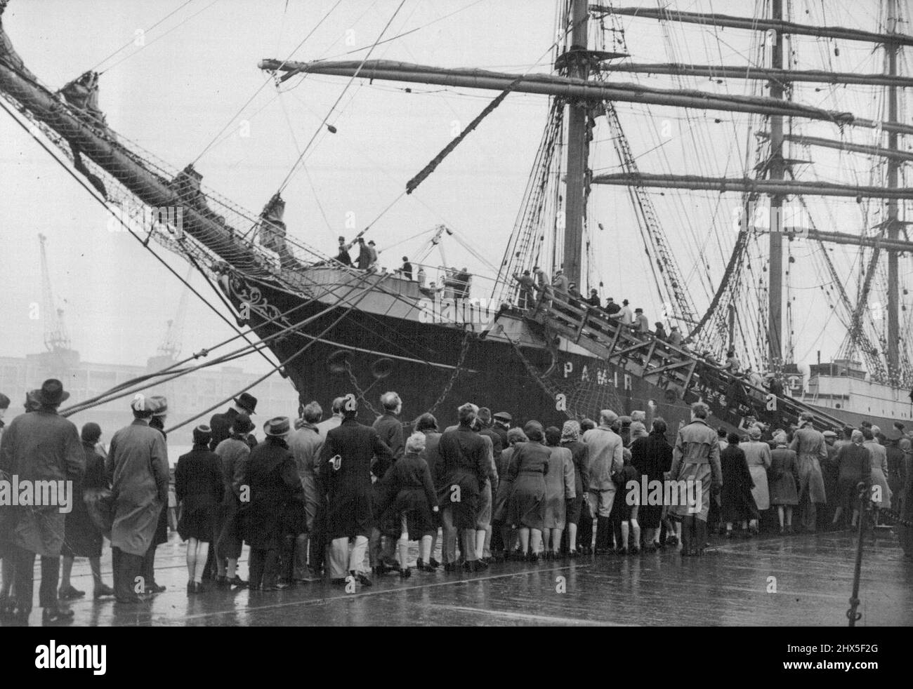 I londinesi vedono il 'Pamir' la lunga coda in attesa di salire a bordo del 'Pamir'. Il barque a quattro alberi 'Pamir' appena arrivato a Londra dopo il suo viaggio di 80 giorni dalla Nuova Zelanda, è stato ora gettato aperto al pubblico, e nonostante il maltempo, molte centinaia di londinesi hanno visitato la famosa nave a vela nel Victoria Dock. Dicembre 29, 1947. (Foto di Sport & General Press Agency, Limited). Foto Stock