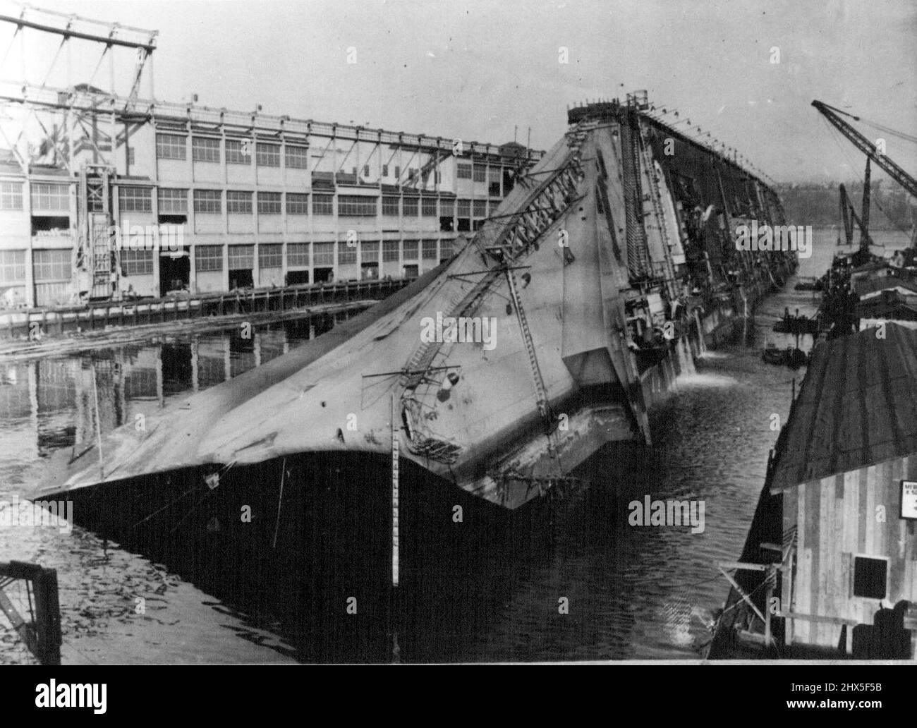Lentamente, quasi impercettibile, gli U.S.S. Lafayette, l'ex liner francese di lusso Normandie, agosto 7 ha iniziato a essere proprio nel molo del fiume Hudson, New York City. Dove si rotolò sul suo lato dopo che la sua sovrastruttura divenne pesante con tonnellate di acqua versato in lei per spegnere un fuoco eviscerante. Waterpags dal suo scafo agosto 7, come operazioni di salvataggio ha iniziato a destra la regina una volta dei mari. Settembre 13, 1943. (Foto di stampa associata). Durante la seconda guerra mondiale, Normandie fu sequestrata dalle autorità statunitensi a New York e rinominata USS Lafayette. Nel 1942, il liner catturò il fuoco mentre era Foto Stock