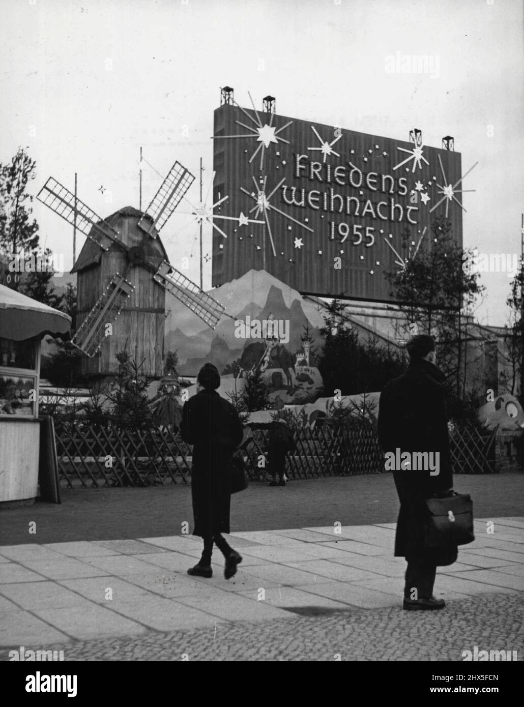 Per augurare loro Un Buon Natale..... Una sezione del mercato di Natale con il suo mulino a vento decorativo e set-pezzi e l'enorme 'Natale 'Pace' 1955 slogan. Nell'ex giardino del piacere a Marx-Engles-Platz a Berlino Est, i tedeschi dell'Est hanno eretto un grande mercato di Natale. Tutto il possibile è stato fatto per dare al mercato un'aria festosa ed è solo su un'ispezione più stretta può il visitatore notare le molte inadeguatezze rispetto al cibo occidentale di Natale. I comunisti hanno utilizzato il mercato per una generosa esposizione di slogan propagandistici, tra cui un enorme poster illuminato Foto Stock