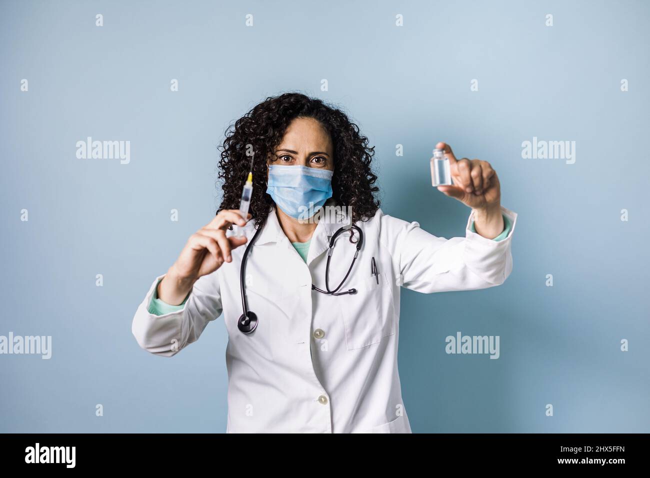 Medico ispanico con capelli ondulati che tiene l'iniezione di vaccino per pandemia in Messico america latina Foto Stock