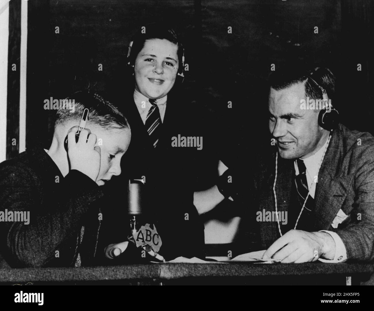 Durante la guerra l'ABC fu responsabile dell'invio di messaggi ai militari australiani all'estero e ai parenti dei bambini britannici che erano stati evacuati in Australia per sfuggire al blitzkrieg tedesco. Qui Jim Pratt aiuta due ragazzi con le tecniche di una conversazione radio-telefonica bidirezionale con i loro genitori in Inghilterra. Gennaio 1, 1941. Foto Stock