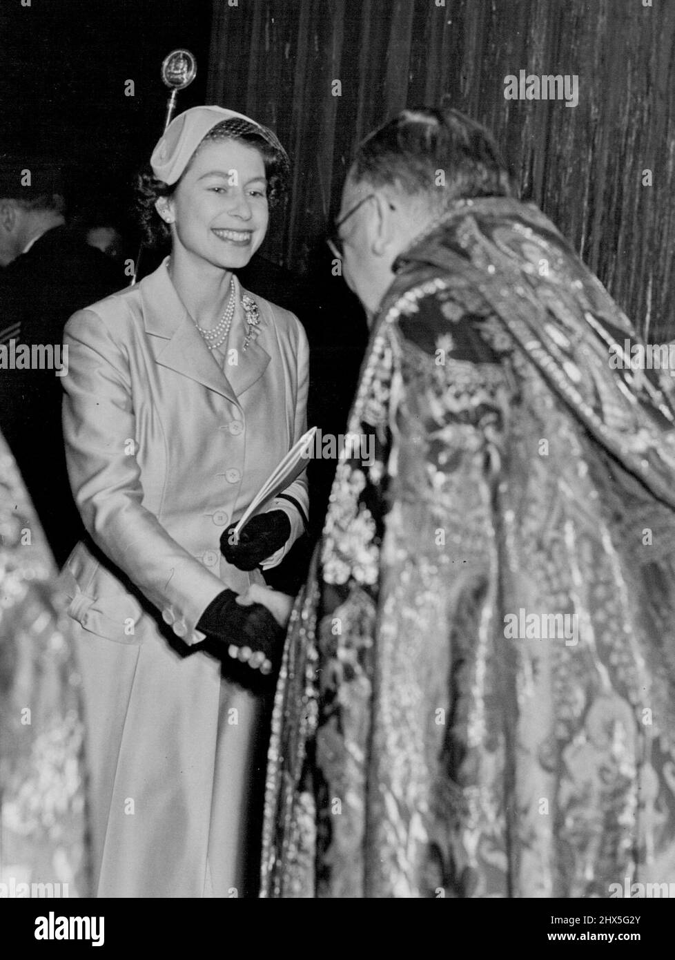 La regina dice buona notte.. con un sorriso caldo e una stretta di mano. Parla con il canone Marcus Knight, della Cattedrale di St. Paul, Londra, dove la Regina ieri sera (24.10.55) ha frequentato il Servizio Nazionale per i marittimi. Indossava un cappotto di seta in una tonalità eau-de-nil con un piccolo cappello giallo. Ottobre 25, 1955. (Foto di Daily Mirror). Foto Stock