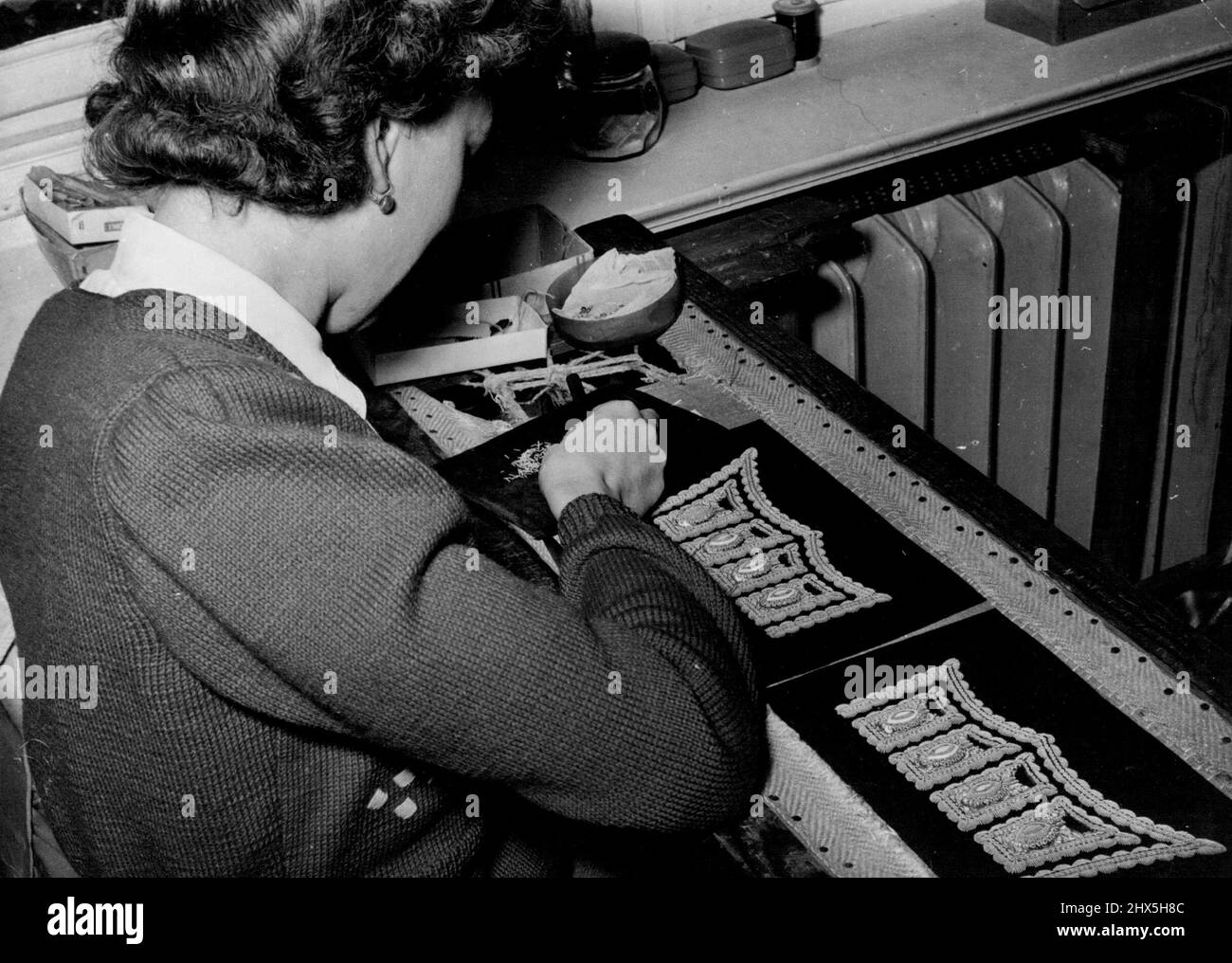 Coronation glitter - prodotto in Germania. Un operaio esperto ha teso la stoffa rossa strettamente sopra un telaio di ricamo - ora le sue dita agili ed un ago fanno il resto. Quando la scintillante processione degli ufficiali delle guardie scorterà sua Maestà all'Abbazia di Westminster il giorno dell'incoronazione, non molte delle innumerevoli migliaia di spettatori sapranno che le loro splendide uniformi saranno state ricamate dai tedeschi volano che si forano in una piccola fabbrica a Berlino Ovest. Aprile 9, 1953. (Foto di Paul Popper Ltd.). Foto Stock