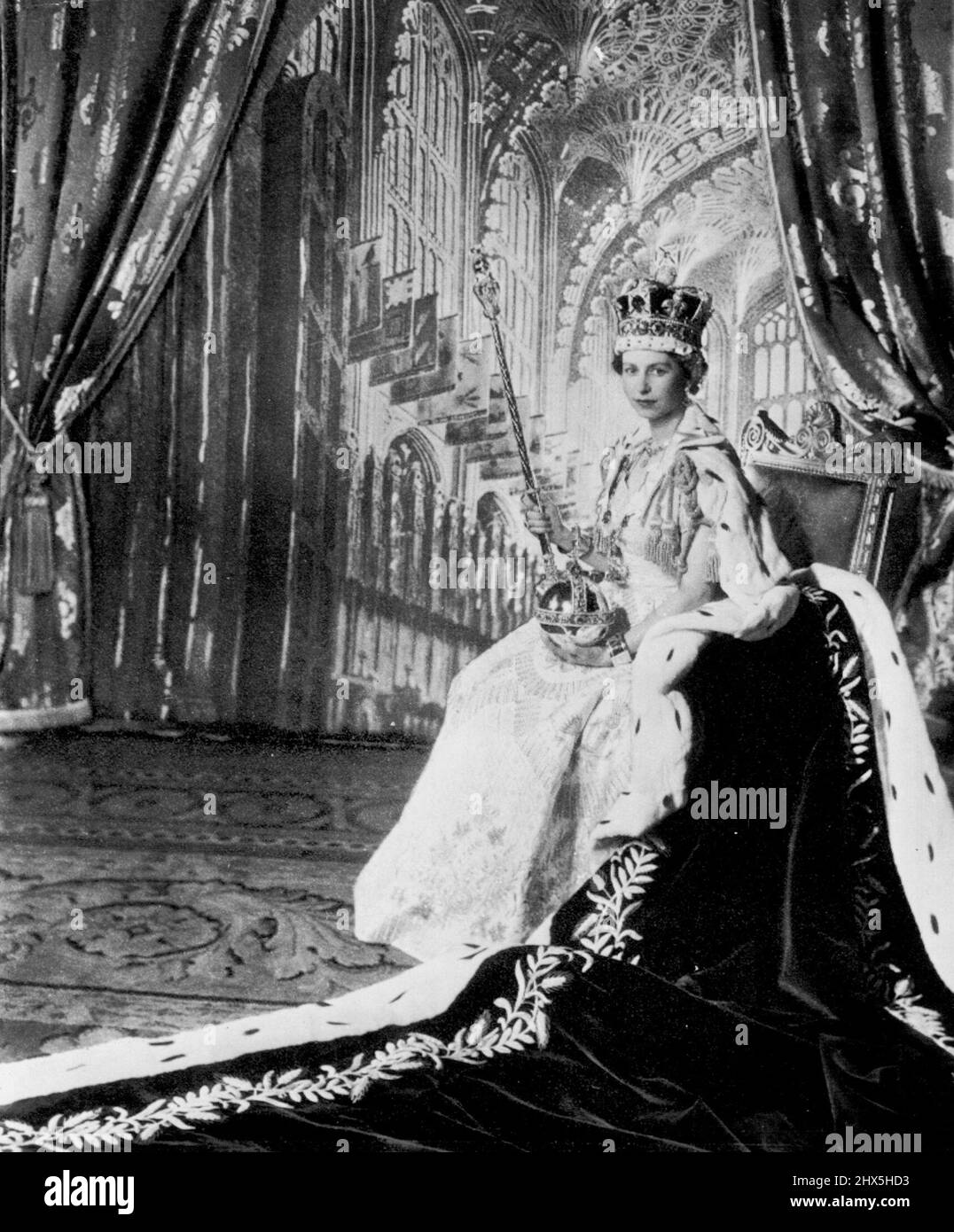 Regal Bearing -- la Regina Elisabetta II, vestita per incoronazione e abito di velluto viola, si pone nella Sala del Trono di Buckingham Palace dopo la sua incoronazione Giugno 2. Sulla sua testa c'è la Corona Imperiale che indosserà in occasioni di stato. Nella sua mano sinistra tiene l'Orb, emblema del potere sovrano e nella sua destra lo scettro con Croce, segno di forza regale e di giustizia. Sui suoi polsi indossa le armature, o bracciali di sincerità. Lo sfondo di questa foto di Cecil Beaton rappresenta la Cappella di Enrico VII nell'Abbazia di Westminster. Giugno 09, 1953. (Foto di AP Wirephoto). Foto Stock