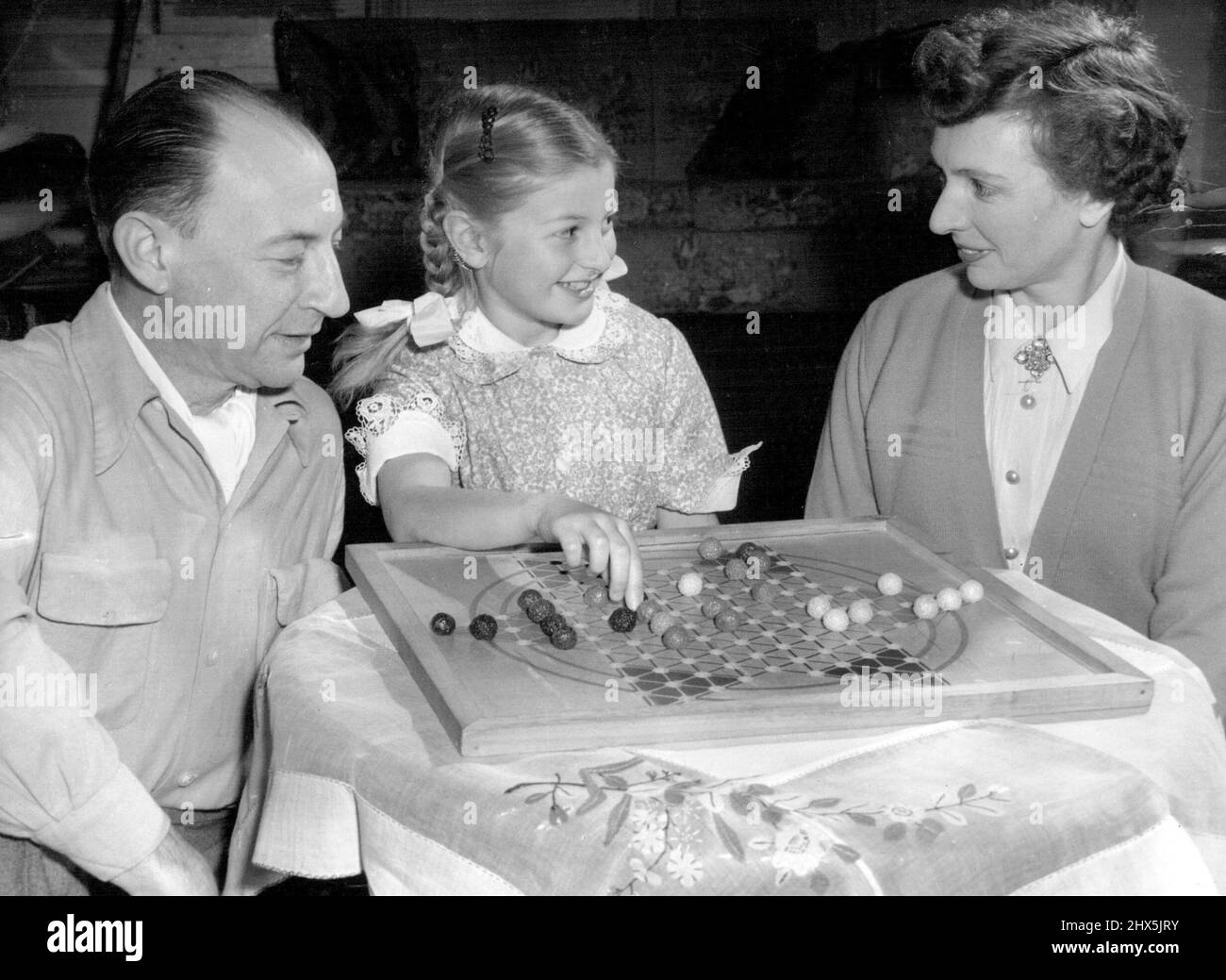 Joseph Post, direttore associato della Sydney Symphony Orchestra, si rilassa con un gioco di dama con la sua figlia di otto anni Nola e la signora Post. Settembre 23, 1954. (Foto di Norman L. Danvers, Australian Photographic Agency). Foto Stock