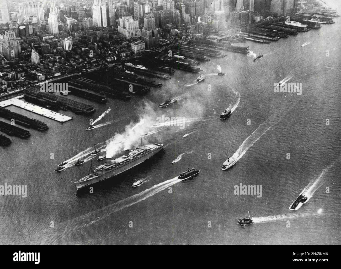 Nuova Regina dei mari finisce più strano Maiden Voyage -- la nuova padrona dei mari, il Cunard ***** Star Liner, la regina Elisabetta, e i suoi sentieri di tigri puffing si sono spostati sul fiume Nord al suo molo ha ricevuto un benvenuto perfunctorio, non per niente in armonia con la sua posizione reale. La sua colorazione camouflage grigio-fango la fece sembrare irreale come un wraith, e servì anche a accorciare le sue linee, in modo che le persone sulla riva non fossero in grado di apprezzare la sua enorme dimensione. Il solito saluto di imbarcazioni portuali ed excussionisti non era parte del quadro perché il suo arrivo quasi senza prefazione fatto anche un Foto Stock