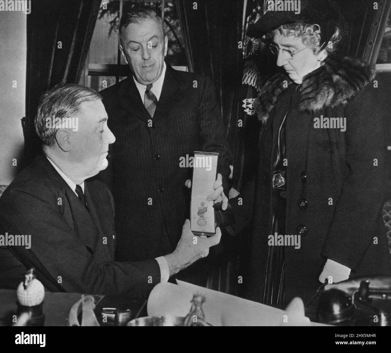 Il Presidente presenta la Medaglia del pilota ai suoi genitori - il Presidente F.D. Roosevelt presenta la Medaglia d'onore del Congresso a MR. E Mrs. Harl Pease, Sr., che l'ha ricevuta per loro figlio, Captain Harl Pease, Jr., il pilota dell'aeronautica militare degli Stati Uniti ha creduto ucciso quando ha fatto un raid audace sopra una base giapponese nel Pacifico nonostante un aereo danneggiato. La citazione letta in parti: 'Per la cospicua galanteria e l'intrepidezza al di sopra e al di là della chiamata di dovere.' Il capitano Pease aveva precedentemente vinto la Croce volante distinta. Febbraio 15, 1943. (Foto di Interphoto News Pictures, Inc). Foto Stock