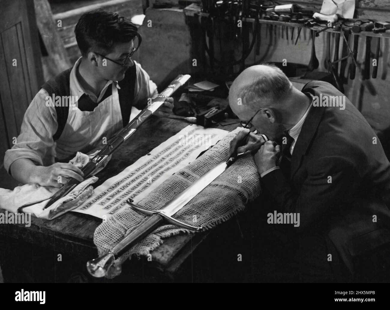 Mostra la Stalingrad Aword Pictures; il Sig. G.T. Amico che mette i tocchi finali all'incisione sulla lama mentre il Sig. L.G. Durbin, responsabile dei supporti in oro e argento sullo scabbard, gli dà un'ultima occhiata. L'incisione sulla lama recita: "All'acciaio. Cittadini di Stalingrad - il dono di re Giorgio VI in segno di omaggio al popolo britannico”. Il dono del Re ai "cittadini di Stalingrad con cuore di teel". Gennaio 03, 1943. (Foto di I.N.A.) Foto Stock