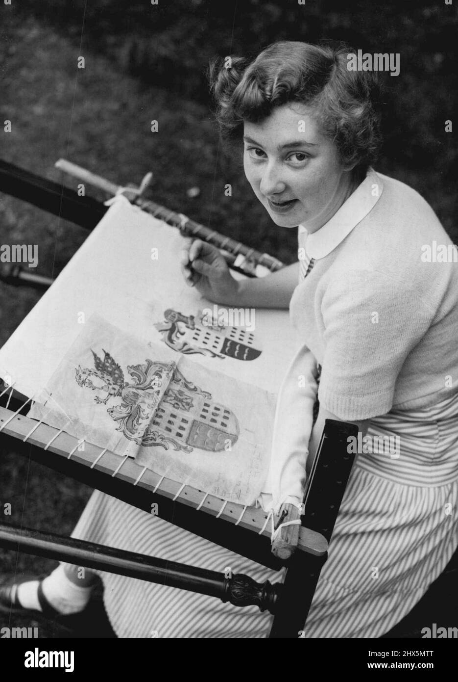 Armi e la Needlewoman -- con abilità scrupolosa, 20 anni Denise Haystaff di Windsor, Berkshire, lavora su un cappotto di armi da ago nel giardino della Scuola di Stitchery e merletto, Bookham, Surrey, là ragazze disabili da tutto il paese sono addestrate per carriere nel lavoro di bisogno. Denise sta recuperando dopo un'operazione del 'bambino blu' e sta imparando condurre una vita normale. La scuola - dove il corso completo dura tre anni - ha fatto il lavoro per la principessa reale, la duchessa di Kent, la regina tarda Maria e molti altri intenditori di ottimo lavoro al bisogno. Luglio 27, 1954. Foto Stock