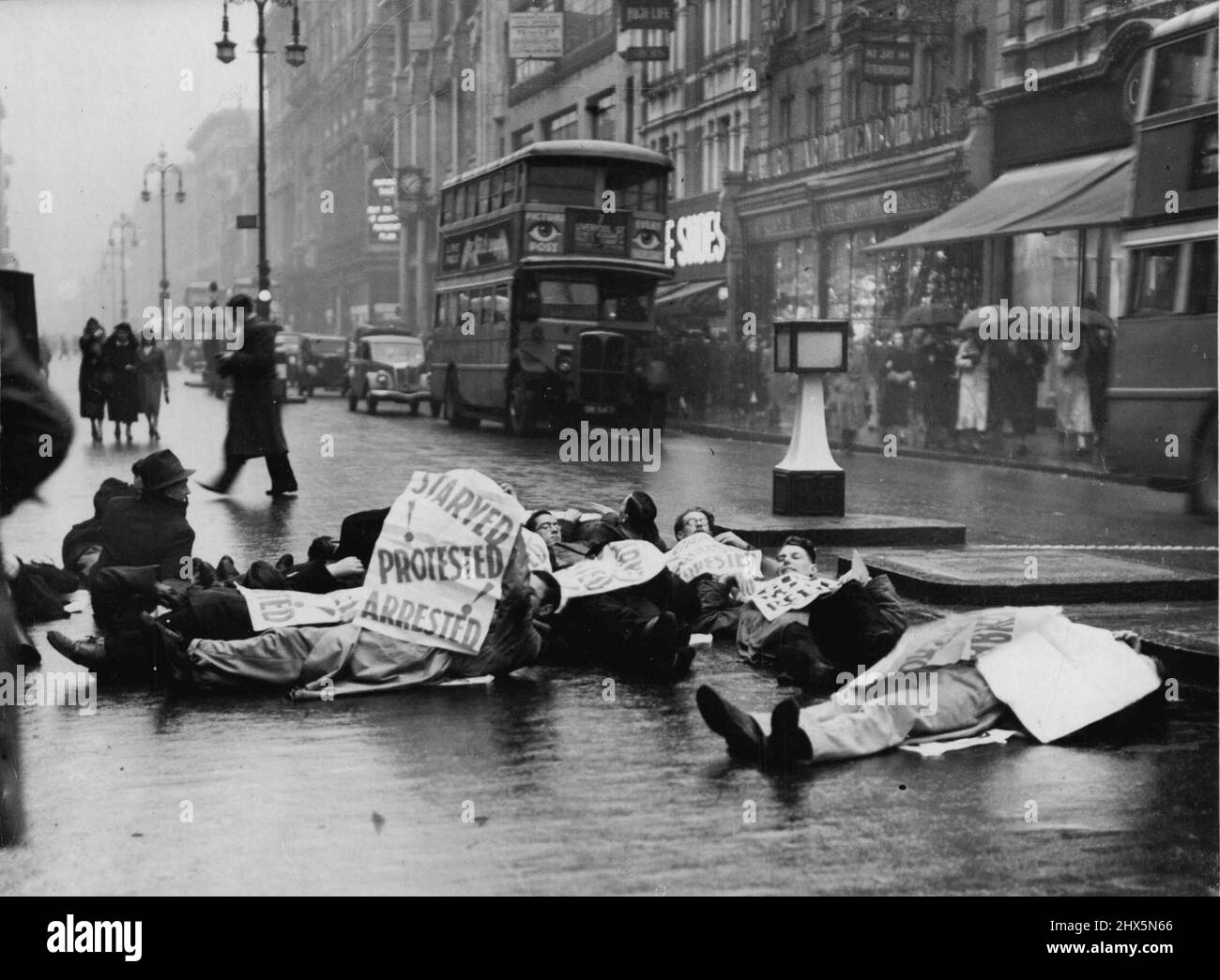 Disoccupati uomini si trovano in basso a Oxford Street -- i disoccupati uomini che si trovano nella strada all'angolo di Oxford Street e Berwick Street. I membri del movimento dei lavoratori disoccupati hanno organizzato oggi un'altra manifestazione quando si sono stese sulla strada all'angolo di Oxford Street e Berwick Street, trattenendo il traffico fino a quando la polizia li ha dispersi. Gennaio 17, 1939. (Foto di Keystone). Foto Stock