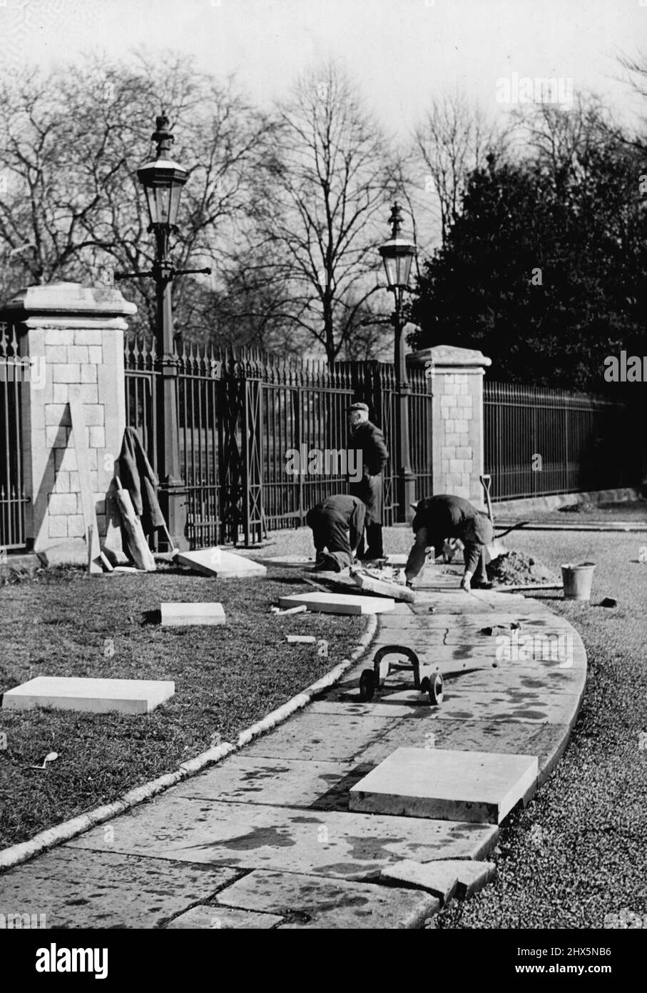 The Last Gate il Re Morto passerà attraverso -- operai che mettono in relazione le bandiere di pavimentazione all'ingresso del cancello che conduce al Long Drive al Castello di Windsor l'ultimo cancello attraverso il quale Re Giorgio VI passerà. Sono in corso vasti preparativi a Windsor, sia nella Cappella di San Giorgio che in città per il funerale di Re Giorgio VI il venerdì. La stazione è appesa in nero e viola, le strade lungo il percorso per il castello sono state liberate da isole, palchi e borchie, e locali commerciali sono stati imbarcati. Febbraio 12, 1952. (Foto di Fox Photos). Foto Stock
