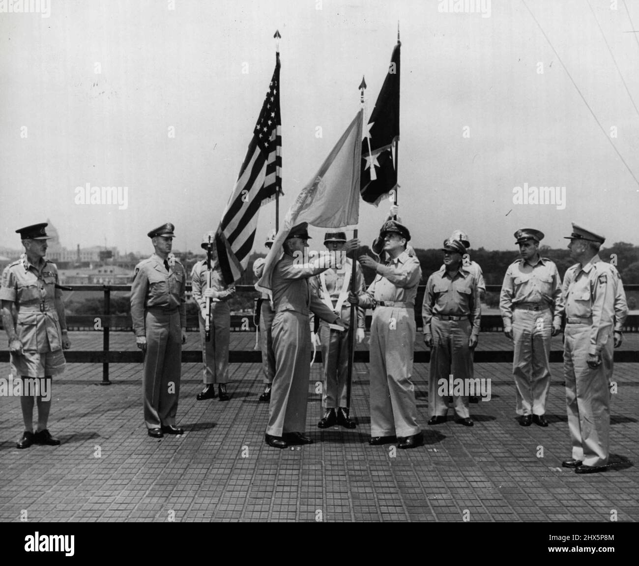 Il generale J. Lawton Collins (centro di sinistra), capo di stato maggiore dell'esercito degli Stati Uniti, è mostrato presentando la bandiera blu e bianca delle Nazioni Unite al generale dell'esercito Douglas MacArthur, Comandante in capo del comando dell'esercito degli Stati Uniti in Estremo Oriente e comandante generale delle forze militari unificate delle Nazioni Unite che assistono la Repubblica di Corea in difesa contro l'invasione comunista nordcoreana. La presentazione si è svolta presso la sede centrale del generale MacArthur a Tokyo, in Giappone. Agosto 21, 1950. (Foto di United States Information Service). Foto Stock