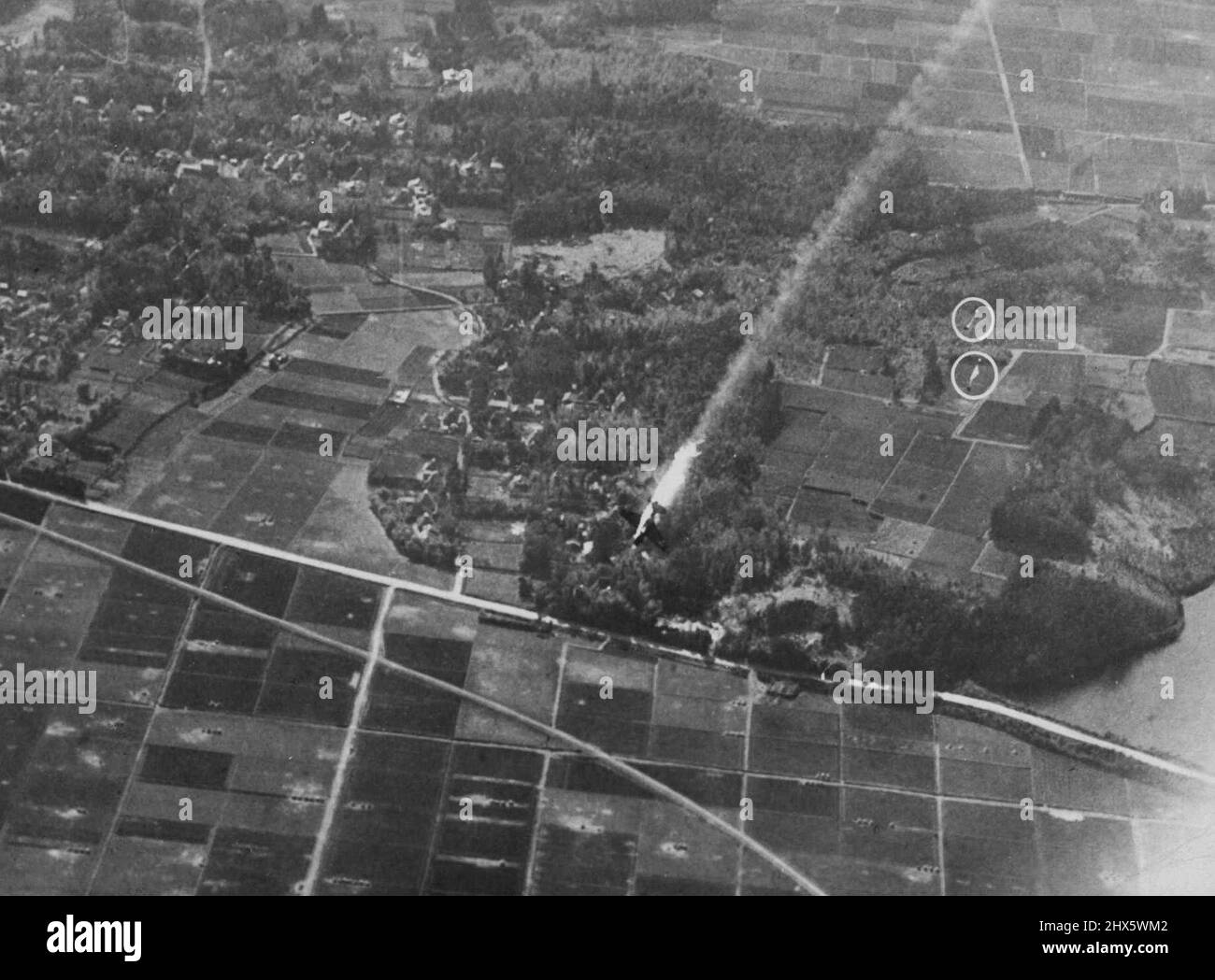 US Plane Shot Down in Attack on Enemy Home Island Airfield -- Un bombardamento di immersione della Marina degli Stati Uniti in fiamme precipita verso la terra dopo essere stato messo in afire durante un attacco al campo aereo di Kanoya, Isola di Kyushu, il 17 marzo 1945. Dietro l'aereo i paracadute del pilota e dell'equipaggio, che sono riusciti a saltare in chiaro, stanno per aprirsi (due cerchi). L'attacco è stato uno dei tanti a Kyushu, la più meridionale dell'isola giapponese Foto Stock