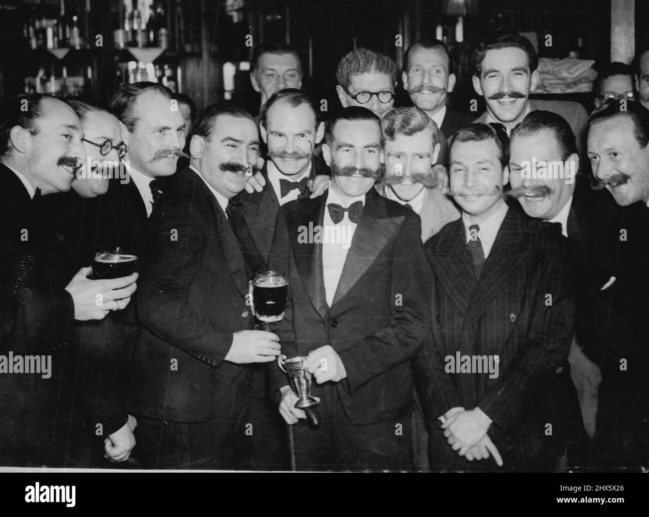 Il proprietario del campione 'Wing Span' e i secondi secondi vincitori del manubrio Club - ex R.A.F. Pilota Alan Gear visto al centro circondato da altri membri durante la seconda cena annuale del manubrio Club, in Fleet Street. Alan Gear ha vinto la coppa del club per la migliore crescita del 1949. L'ex pilota della RAF Alan Gear (al centro) detiene il trofeo del manubrio Club per il miglior alettone nel 1949, quando è stato insignito del titolo in una Fleet St. London, riunitesi per misurare la crescita migliore dell'anno. Foto Stock