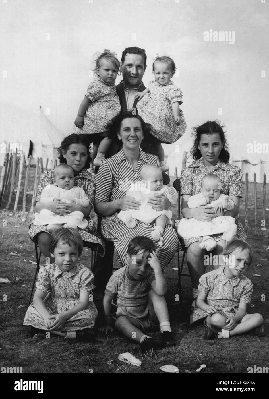 Un Treble, due doppie e tre singoli -- portare-up gemelli ha i suoi problemi, ma quando avete due insiemi di loro, triplette e altri tre bambini, come le Donnellys di Sheerness, allora avete una manciata. Qui la signora Donnelly, Mary (12) e Dolores (11) stanno allattando le triplette di sei mesi, Elizabeth, Eileen e Cecilia-sono stati secondi classificati in un baby show locale-mentre il sig. Donnelly tiene Meave e Monica, i gemelli di 18 mesi-vecchio. Davanti Rosaleen e Caterina, di cinque anni, siediti con tre-voi Foto Stock