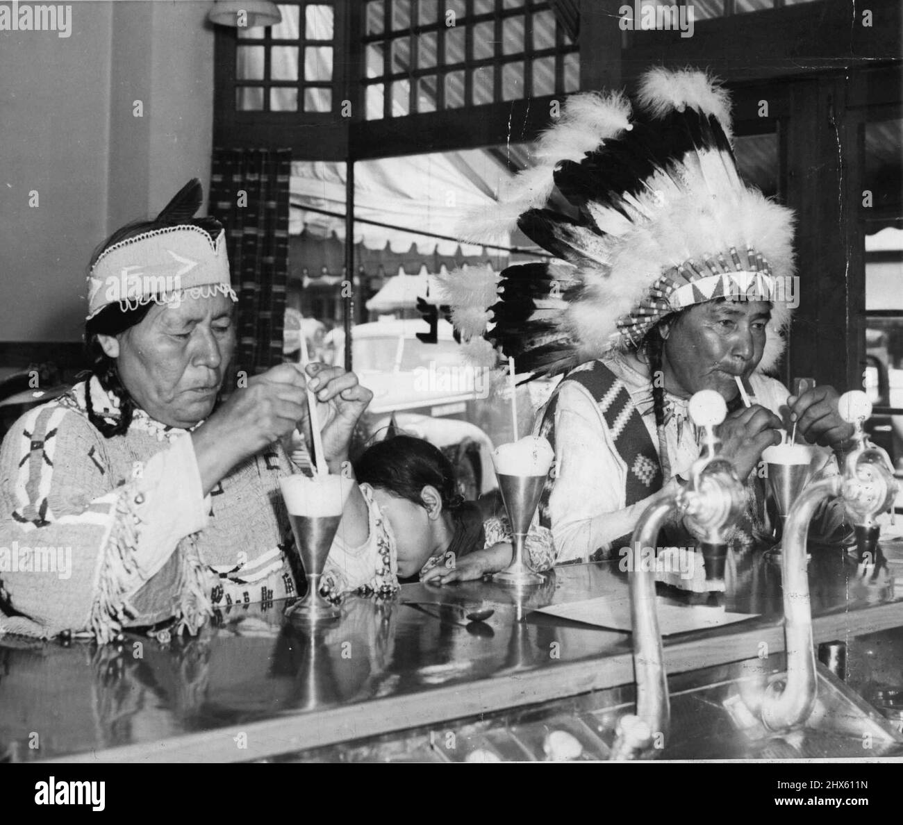 La fine di un giorno occupato -- Chief Spotted Eagle e la sua donna di nuvola rossa di squaw finiscono il loro viaggio di shopping indulgendo in una soda di Strawberry. La loro figlia di otto anni, Big Bird Woman (Centro), era un po' timida. Gennaio 11, 1941. (Foto da Associated Press Photo).;la fine di un giorno occupato -- Chief Spotted Eagle e la sua donna nuvola rossa squaw finire il loro viaggio di shopping indulgendo in una soda di fragola. La loro figlia di otto anni, Big Bird Woman (Centro), era un po' timida. Foto Stock