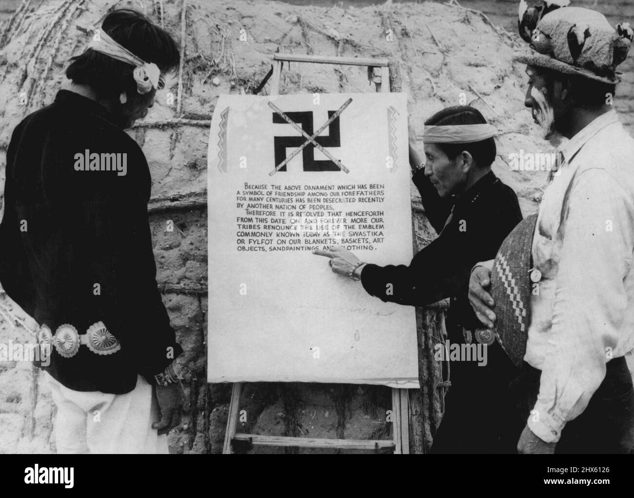 Gli Indiani dell'Arizona hanno beffato la Swastika a causa degli indiani nazisti 'atti di oppressione' che studiano la proclamazione che vieta l'uso della swastika visualizzata in una cerimonia in cui coperte e vestiti recanti il simbolo ora impopolare sono stati bruciati. Da sinistra a destra, Charley Turquoise (Navajo Indian), ***** (Apache indiano). Il dispiacere di "atti di oppressione" nazisti ha portato quattro tribù indiane a rinunciare all'uso del disegno della Swastika indiana sulle loro coperte e cesti, nonostante il fatto che la S indiana Foto Stock