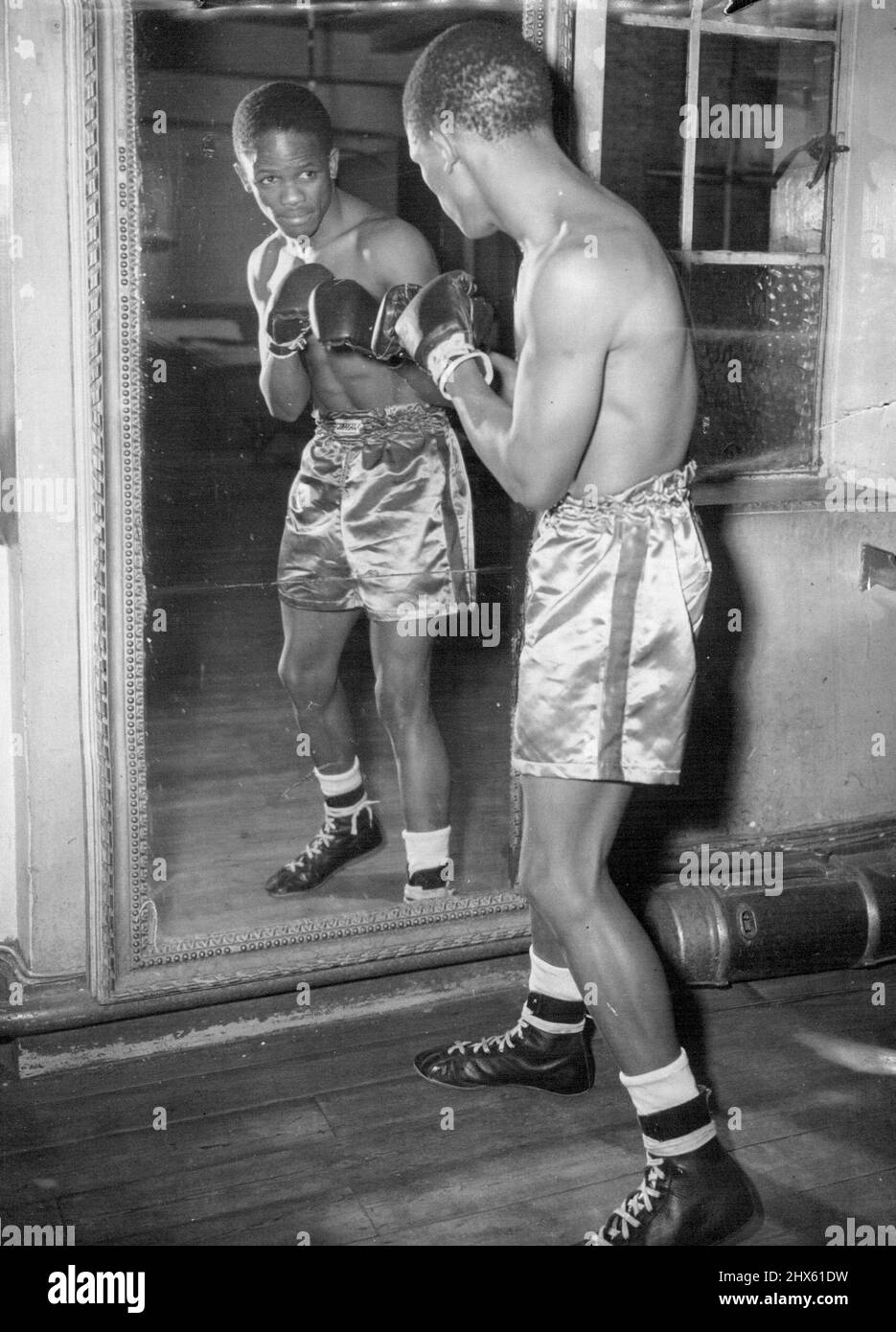 Tattiche specchi -- pugilato ombra con l'aiuto di specchio ***** Jake Tuli Zulu Boxer e il nuovo campione di peso volante dell'Impero, in trim al Cambridge Gymnasium di Londra, dove sta preparando il 1hr il suo faticoso programma autunnale. Jake è previsto per combattere a Newcastle è il 13 ottobre, e ha partite più tardi a Lanchester e Londra. Il nuovo campione del peso del volo del New Empire Jake Tuli, uno Zulu, si spare all'ombra davanti ad uno specchio, a Londra. Un pugnatore pesante e spietato, è alla ricerca di un titolo mondiale bout. Settembre 2 Foto Stock