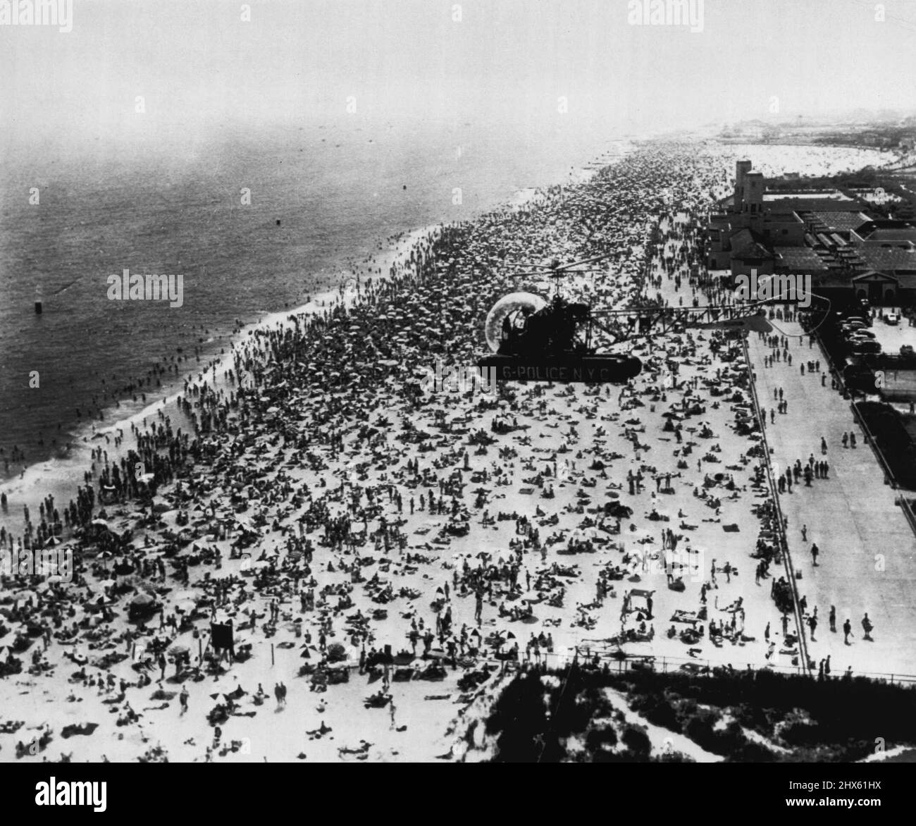 New Yorkers Flock to Beach - Un elicottero di polizia si libra sopra l'affollato parco Jacob Riis in Queens qui ieri, come temperature di 90 gradi più inaugurato in estate e ha inviato i troni che si floccano alle spiagge. Area delle pattuglie in elicottero per impedire alle barche a motore di avvicinarsi troppo alla riva. Giugno 22, 1953. (Foto di AP Wirephoto).;New Yorkers Flock to Beach - Un elicottero della polizia si libra sopra il parco affollato di Jacob Riis in Queens qui ieri come temperature di 90 gradi più di più di inaugurò in estate e ha inviato i throngs fl Foto Stock