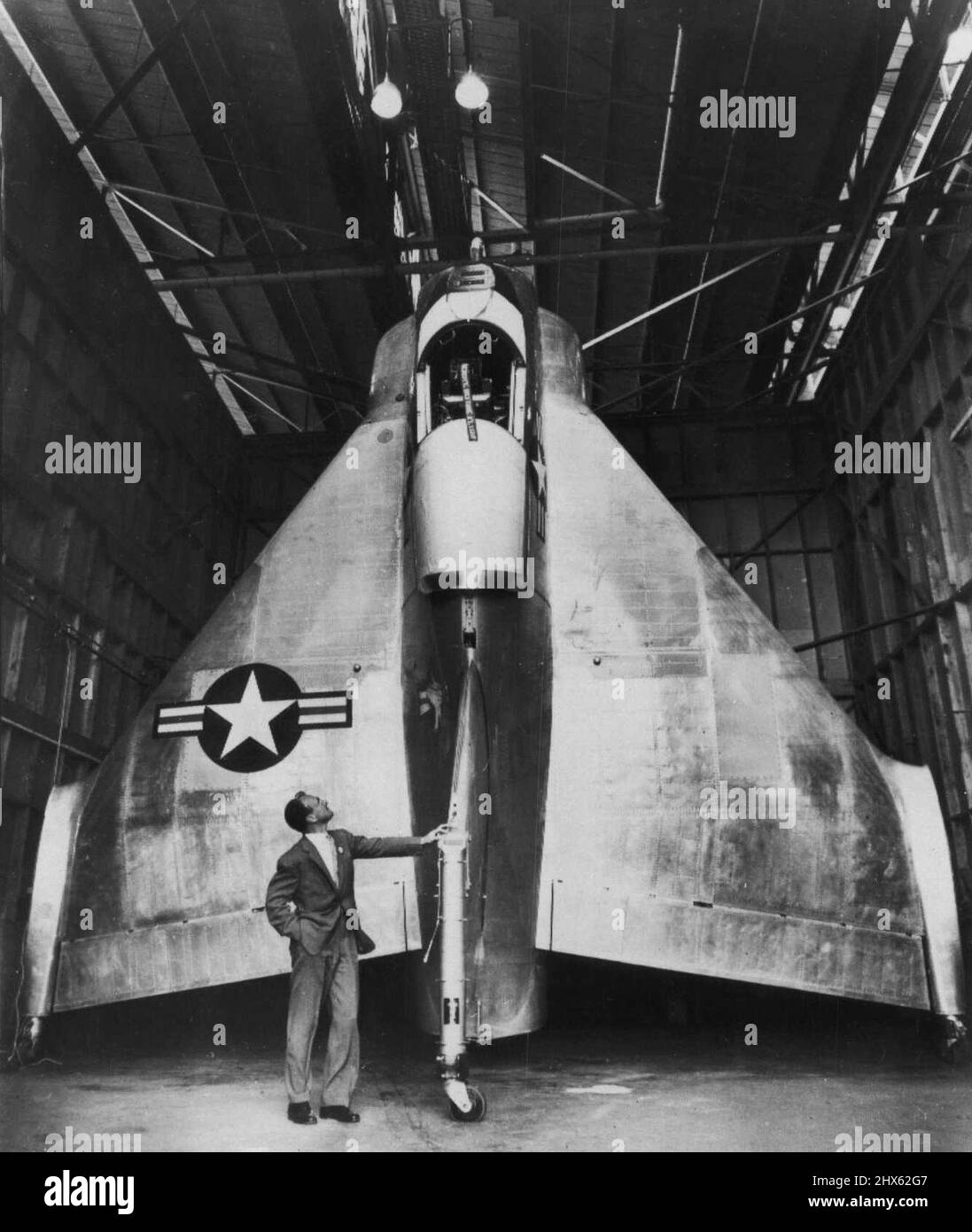 He'll Pilot Vertical Takeoff Plane -- Test Pilot James F. (Skeets) Coleman, 35, guarda al rivoluzionario aereo verticale di decollo che ha in programma di pilotare sui suoi primi voli di prova nel prossimo futuro. L'aereo, costruito da consolida-velivolo Vultee per la Marina, si siede sulla sua coda e si decolera dritto. Torna a terra, coda prima, quando atterrano. Le eliche controrotanti erano state rimosse quando questa foto è stata scattata ieri. Lockheed aereo ha fatto un aereo simile Foto Stock