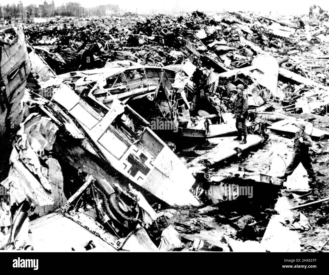 Luftwaffe Graveyard il relitto degli aerei tedeschi riempie un 'cimitero' dietro una fabbrica di alluminio a Grevenbroich, in Germania, dove il rottame era stato portato per il recupero. Due soldati americani (in primo piano a destra) esaminano i resti di un aereo tedesco. Nella zona sono stati rinvenuti anche i naufragi di alcuni aerei americani e britannici. Settembre 4, 1945. (Foto di stampa associata). Foto Stock