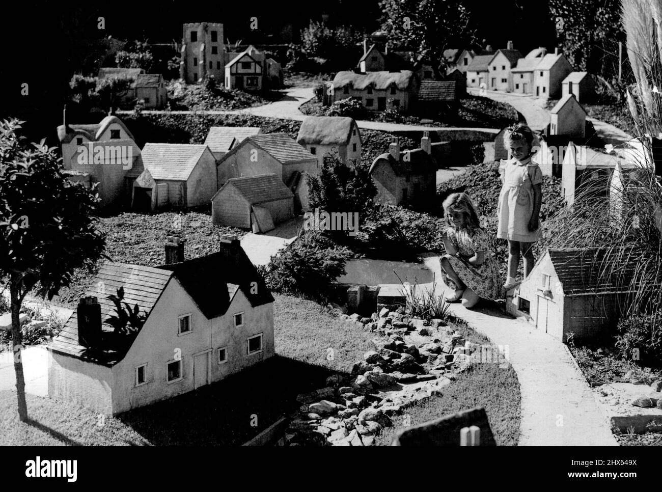 Fairyland in miniatura -- Villaggio del suo proprio - Janice (inginocchiato), introduce la sua piccola amica Pamela Lawton al suo villaggio. Janice Palmer, di Southampton, di quattro anni, ha una propria fairyland in fondo al suo giardino. Suo padre ha costruito per lei un villaggio inglese in miniatura, in un ambiente delizioso a poche centinaia di metri dal trambusto e il trambusto del traffico principale-letto. Il sig. Palmer, un camionista, ha speso più di un anno che costruisce il villaggio che vanta una chiesa, smithy, villaggio Foto Stock