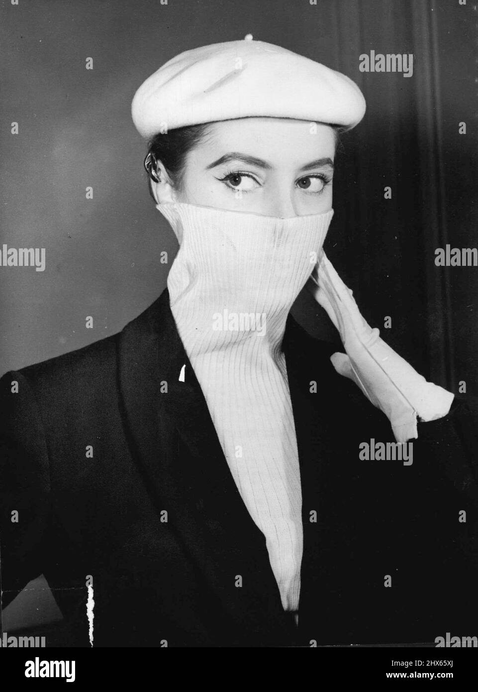 Smog Suit - ora abbiamo la Smog Suit in barathea marina con la nuova linea Princess-e saresti pronto per smog o per quelle giornate cristalline con la maglia bianca adattabile che può essere indossato con la parte superiore rivolta verso l'alto per proteggere la bocca e il naso o girati verso il basso nel senso normale. Questa nota di moda all'ultimo minuto proviene dalla collezione Ian Meredith mostrata a Londra. Novembre 12, 1953. (Foto di Reuterphotos). Foto Stock