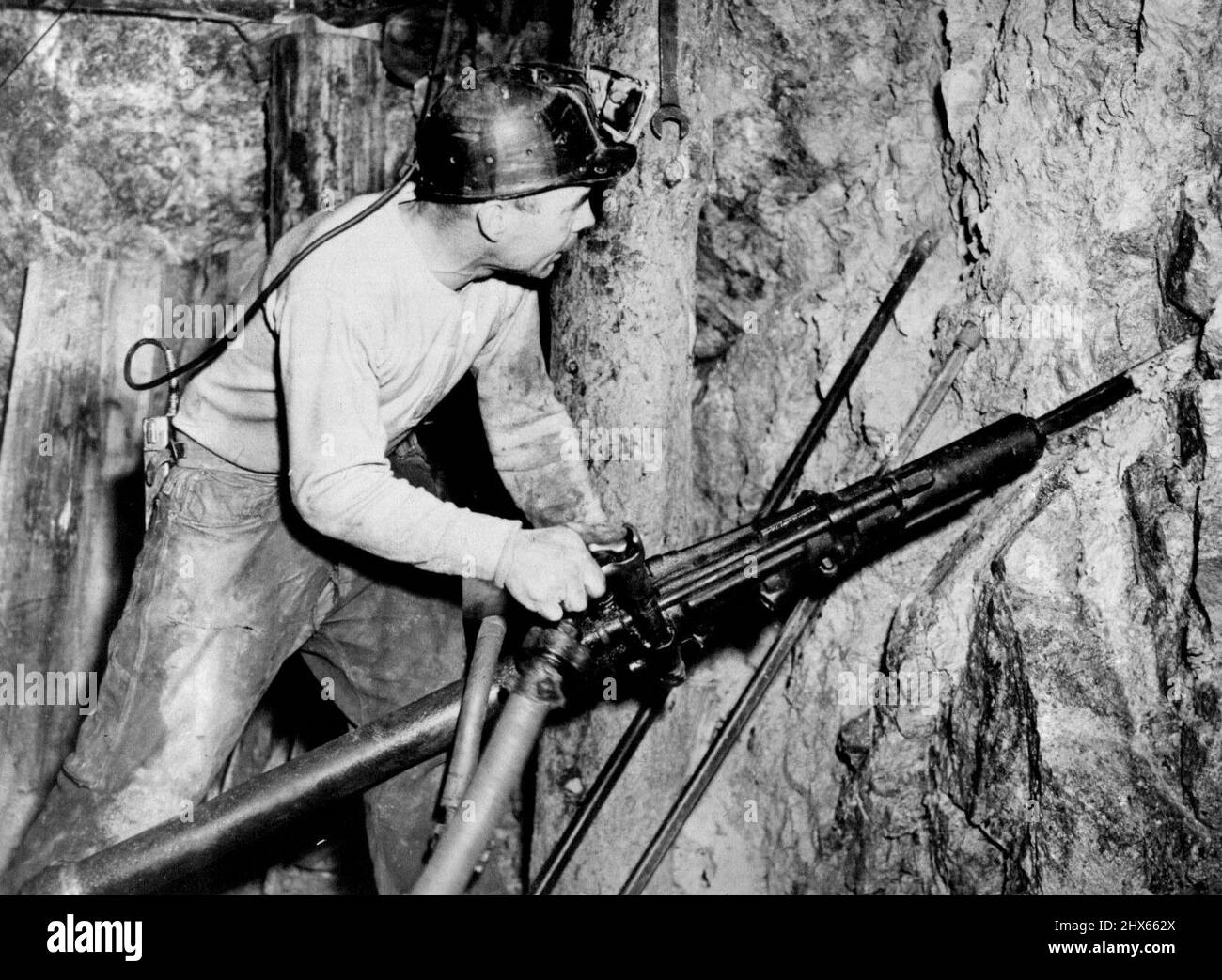 Manganese per le macchine da guerra dell'America - profondo nella miniera di Anaconda nello stato occidentale del Montana, un minatore usa la sua 'pistola' per scavare manganese dalla roccia dura. La sua arma è un trapano ad aria compressa con un collegamento per l'acqua che elimina la polvere. Ottobre 1, 1942. (Foto di Interphoto News Pictures, Inc.) Foto Stock