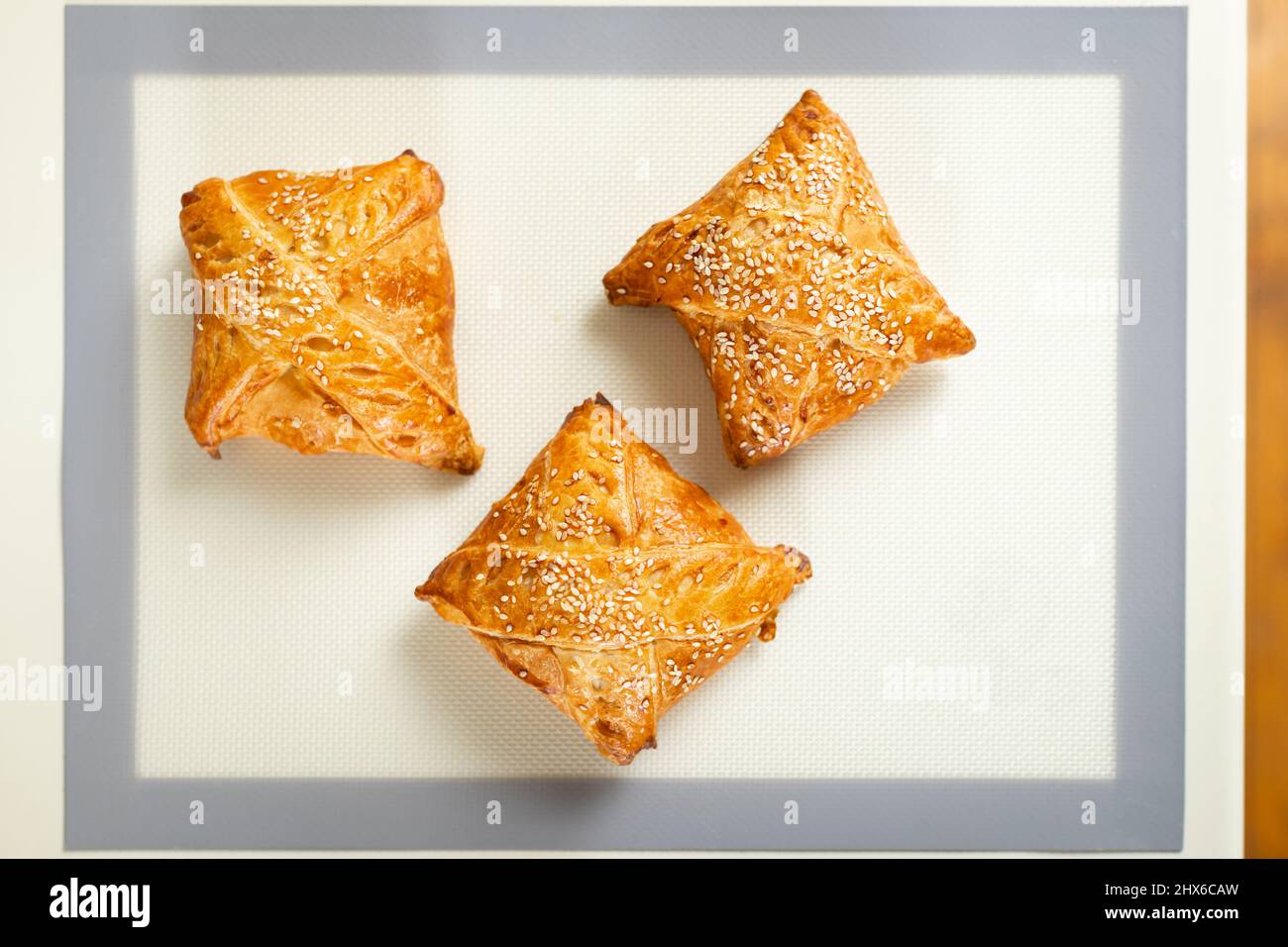 Vista dall'alto della samsa appena sfornata sul tappeto da forno sul tavolo da cucina. Foto Stock