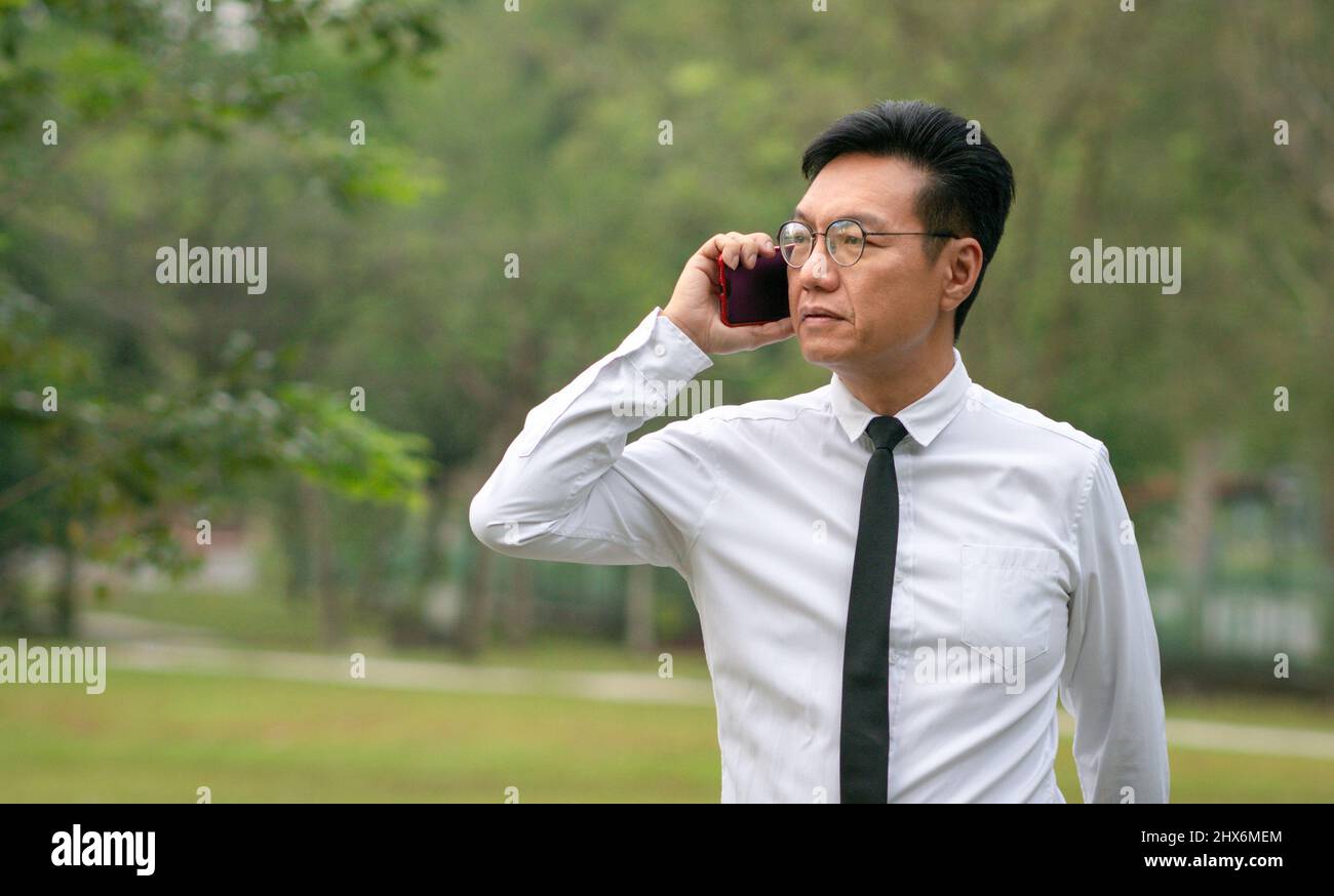Uomo d'affari asiatico maturo che ha una telefonata all'aperto. Spazio di copia. Foto Stock