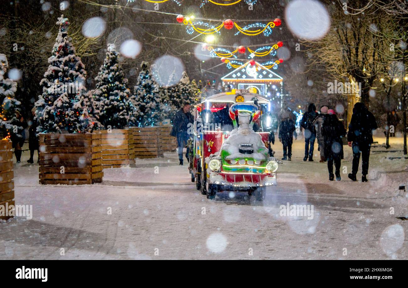 Strada della città innevata con alberi di Natale e decorazioni luminose di notte. Foto Stock