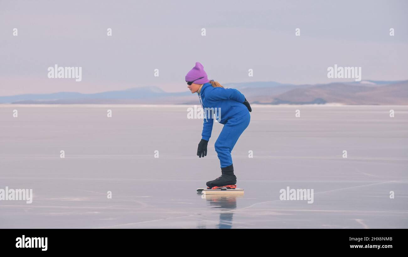 Il treno per bambini su ghiaccio professionale velocità pattinaggio. La ragazza pattina in inverno in abbigliamento sportivo, occhiali sportivi, vestito. Velocità di pattinaggio per bambini pista corta lunga, sport per bambini. Slow motion per esterni. Foto Stock