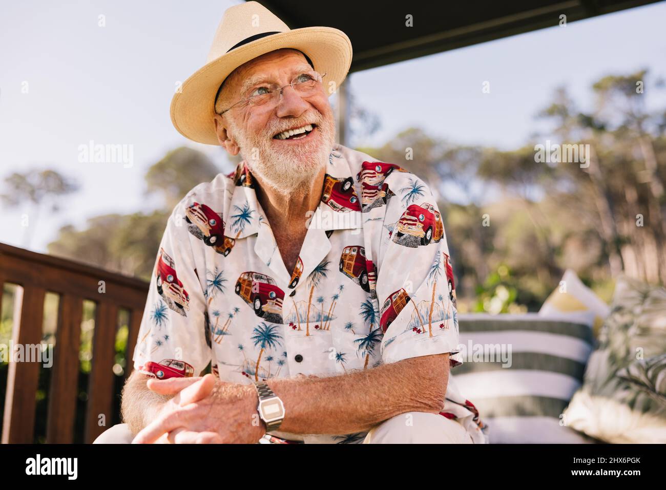 Godere della vita dopo il pensionamento. Uomo anziano felice che guarda via allegro mentre si siede su un divano in un resort spa di lusso. Spensierato uomo anziano godin Foto Stock