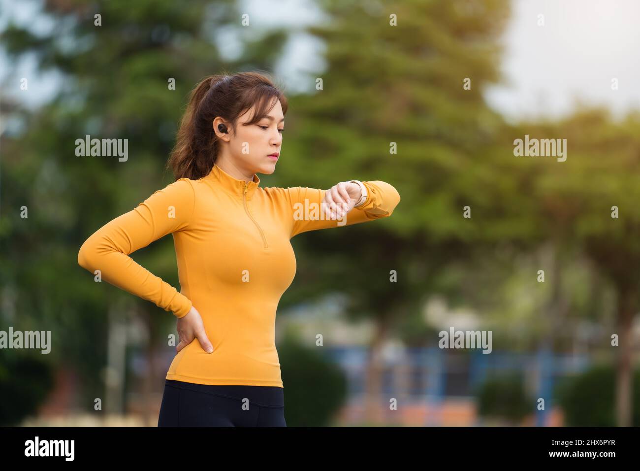 giovane donna che corre e guarda il suo elegante orologio da polso nel parco Foto Stock