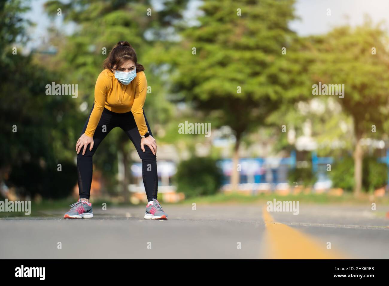 Donna runner stanca con maschera medica per proteggere la pandemia di Coronavirus (Covid-19) Foto Stock