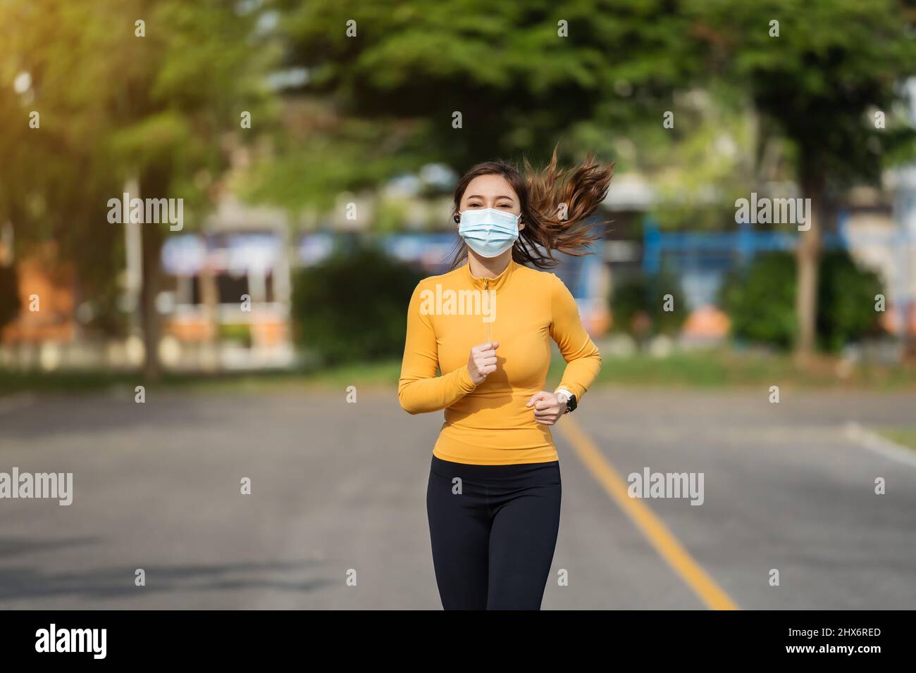 Giovane donna che corre con maschera medica per proteggere Coronavirus (Covid-19) pandemia Foto Stock
