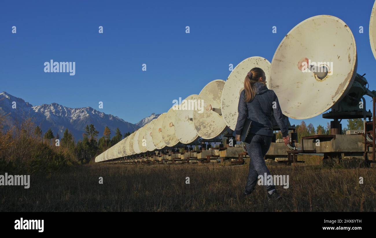 Donna studente operatore di Istituto di fisica solare terrestre monitora le apparecchiature di comunicazione in notebook. Cannocchiale radio solare a schiera unico. Sun Solar radio Telescope. L'osservatorio 'Quasar' a Badary, Russia. Piatti satellitari in montagna. Foto Stock