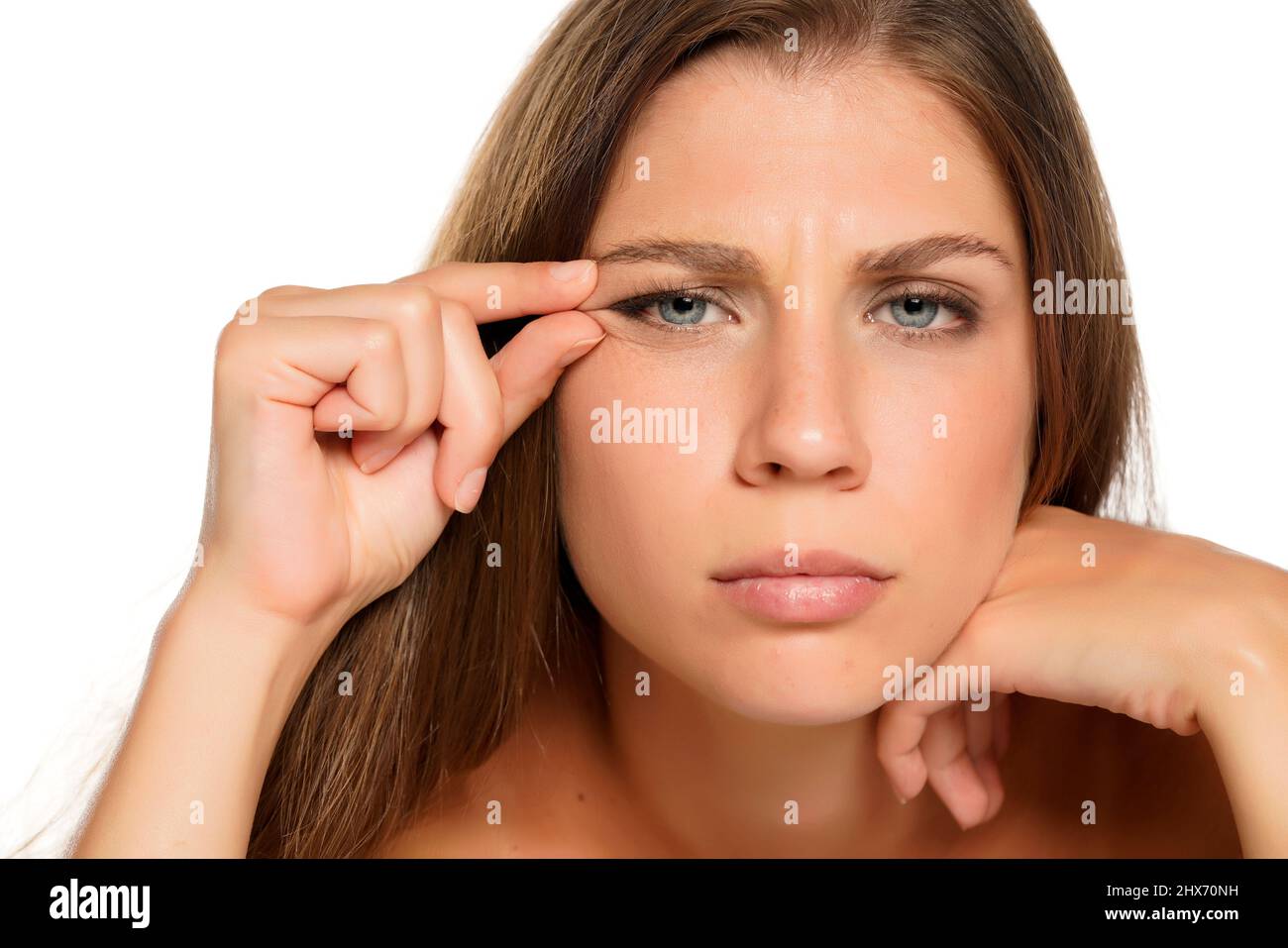 una giovane bella donna nervosa con occhi blu che le stringe le rughe intorno ai suoi occhi su uno sfondo bianco Foto Stock