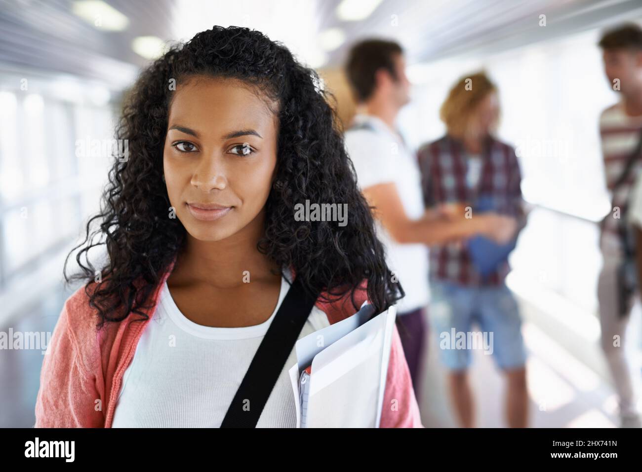Shes pronto per il semestre. Ritratto di una giovane studentessa attraente in piedi con i suoi amici sullo sfondo. Foto Stock
